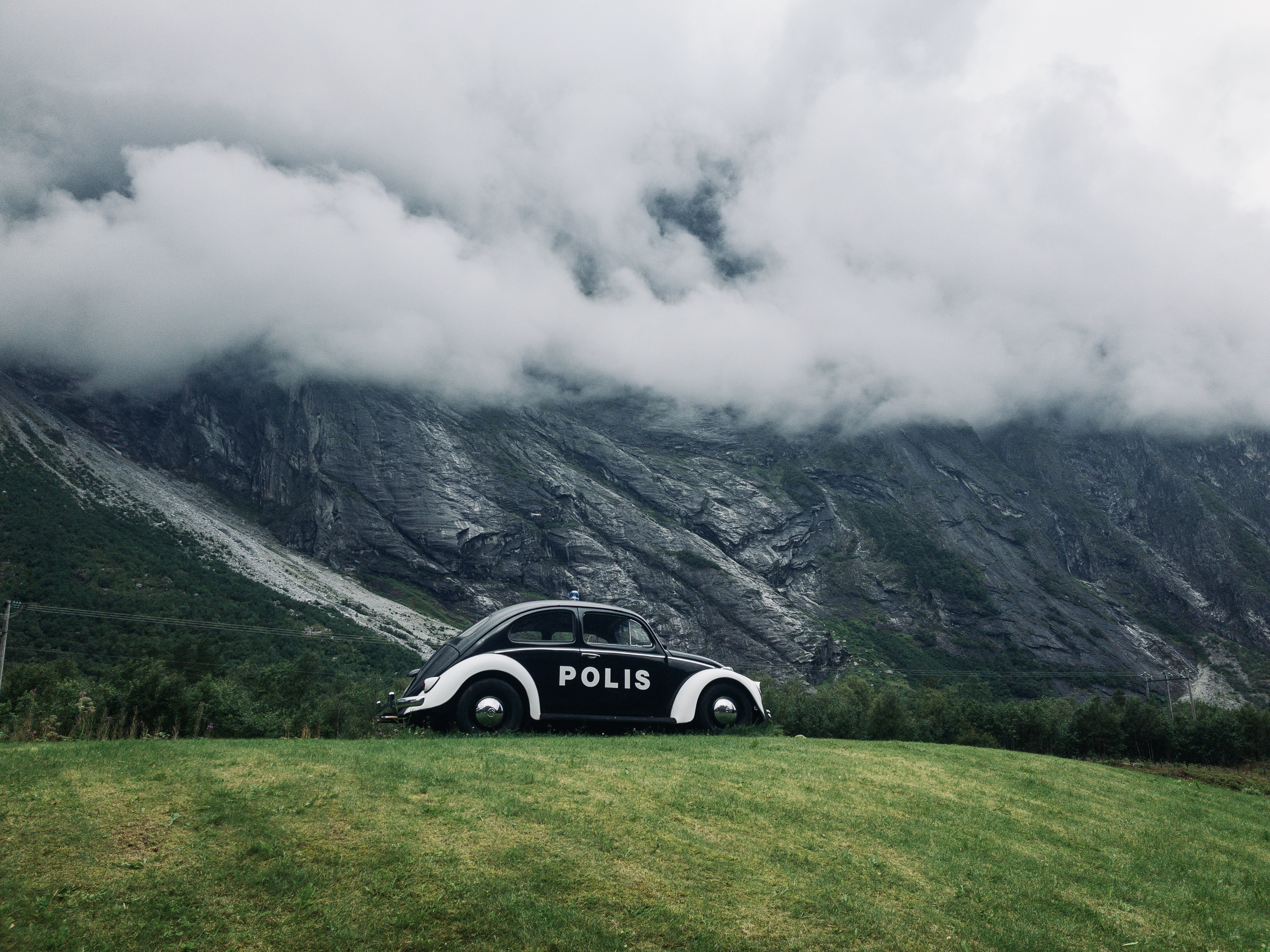 The troll wall Norway with an old fashioned black and white police car in front of it.