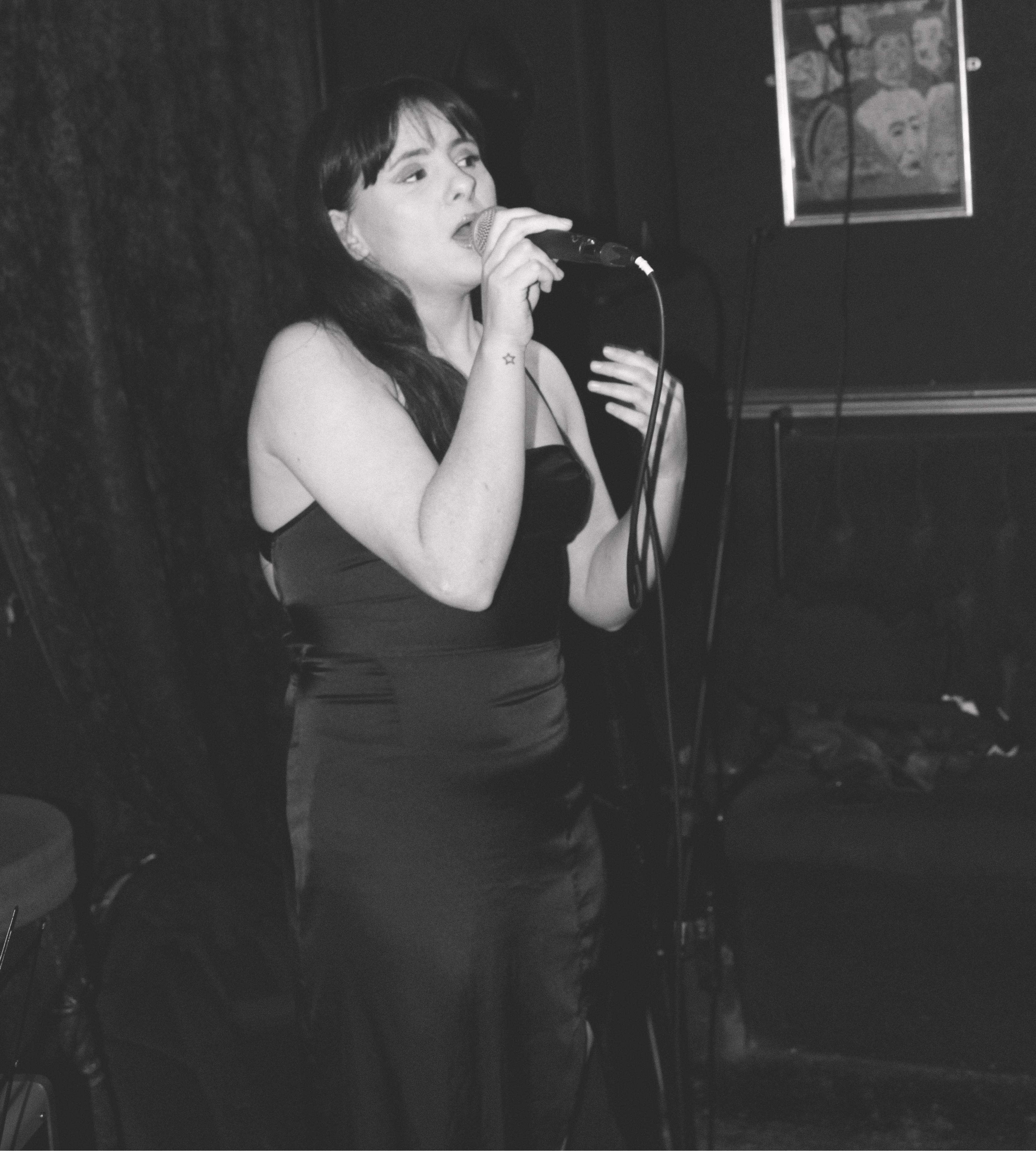 a black and white photo of Kiera singing into a microphone