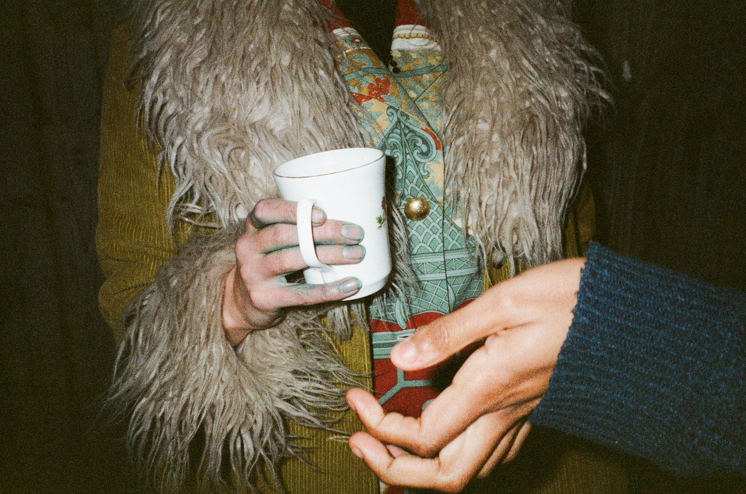 a photo taken by connor of a person holding a mug wearing a fur vest