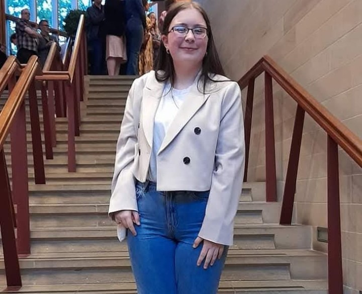 Kaila standing on a staircase smiling at the camera