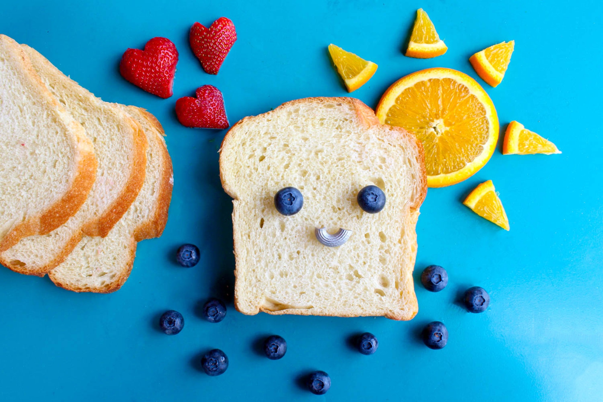 Picture of a slice of bread with blueberries making a smiley face