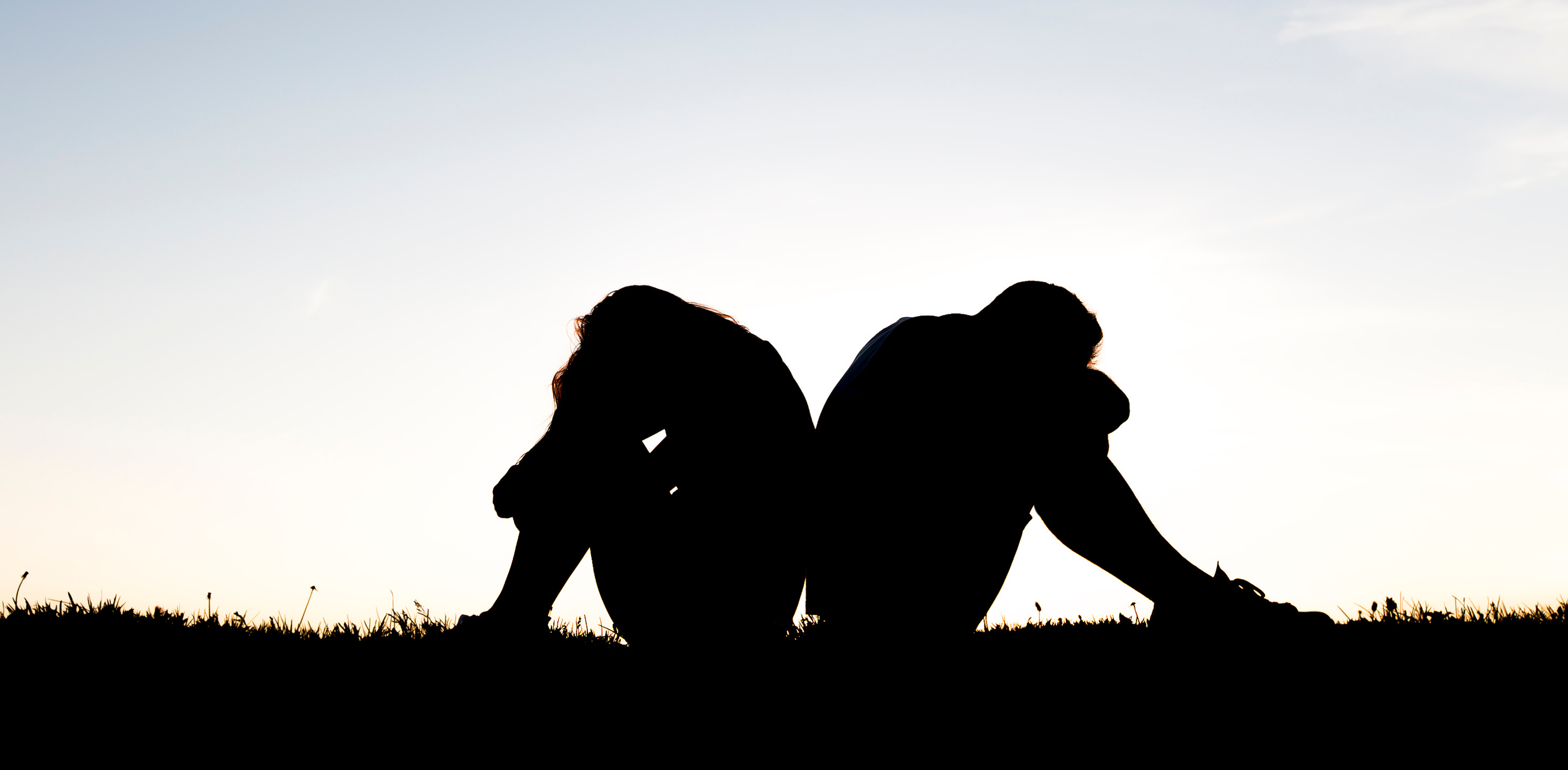 the silhouette of a couple sitting with their backs to each other