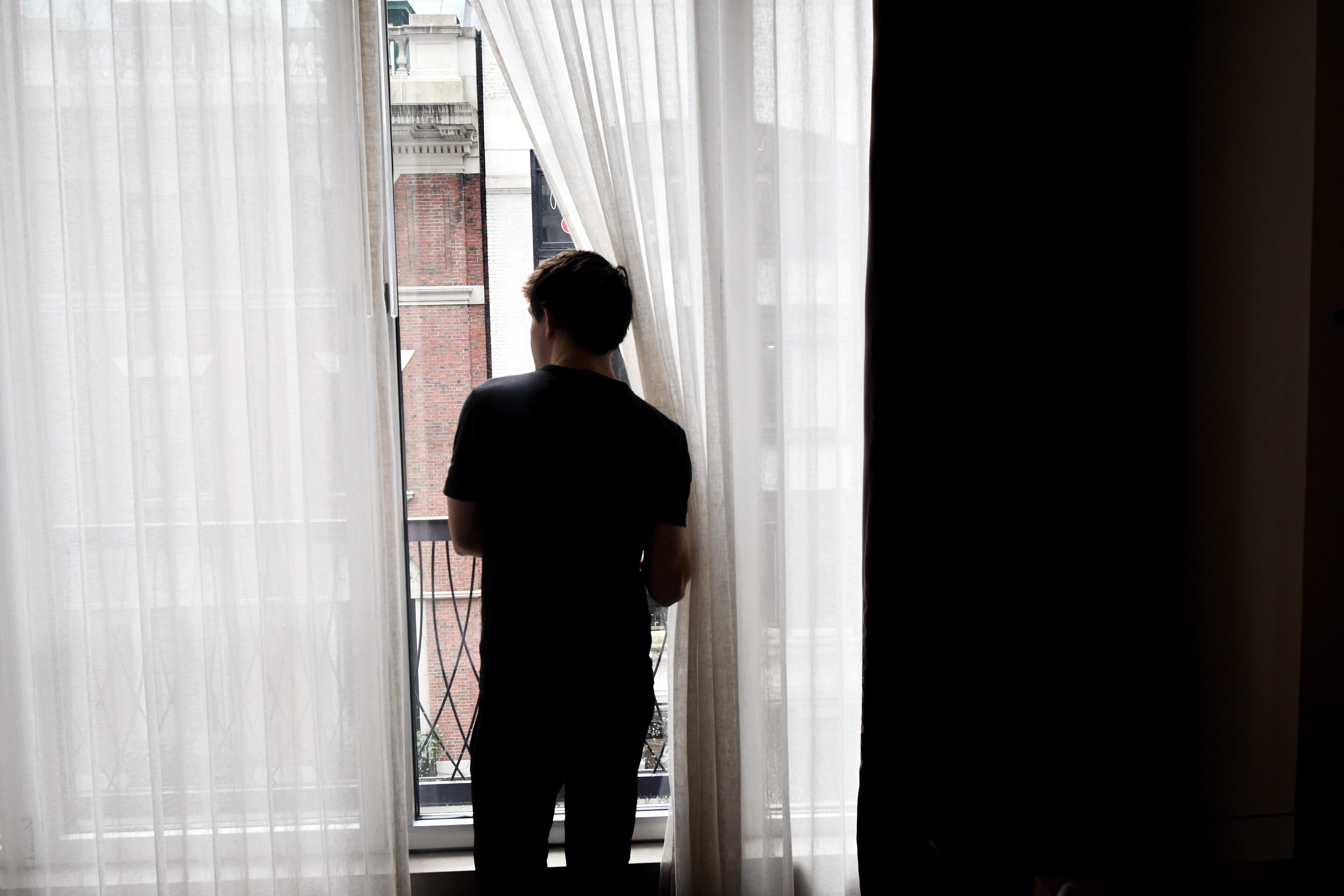 young man looking out his window