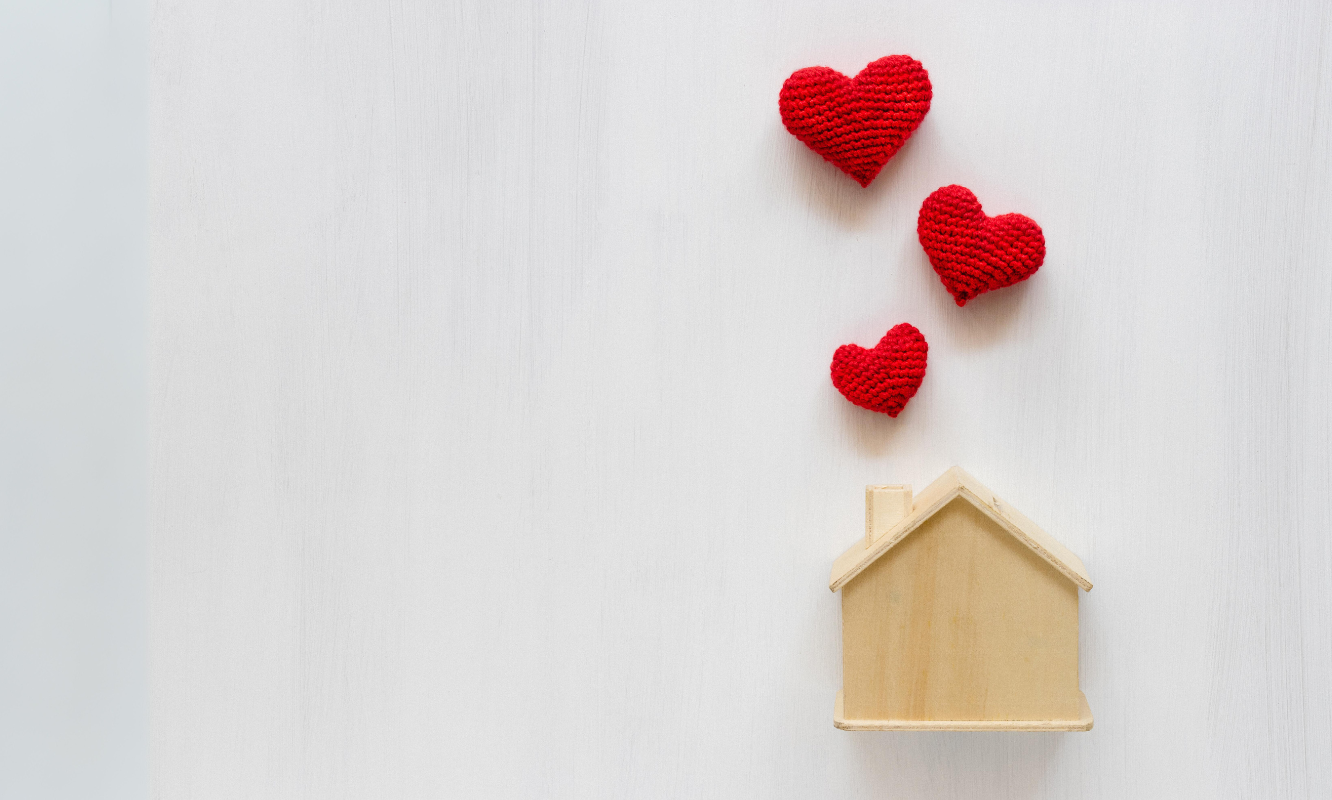 a wooden house shape with hearts coming out of the top