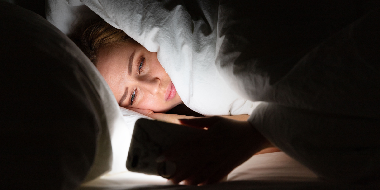 woman looking at her phone in bed 