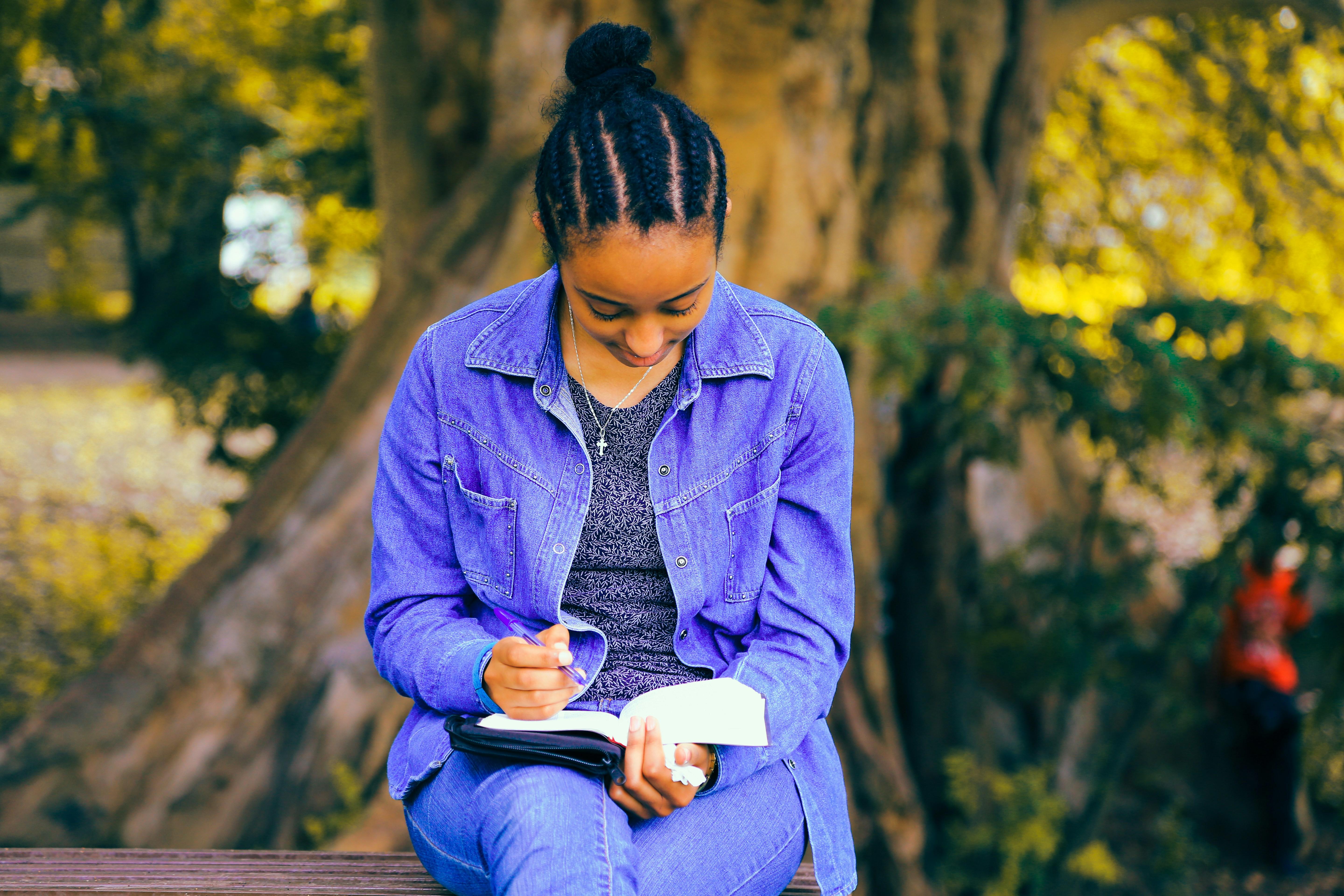 woman sitting on a bench writing 