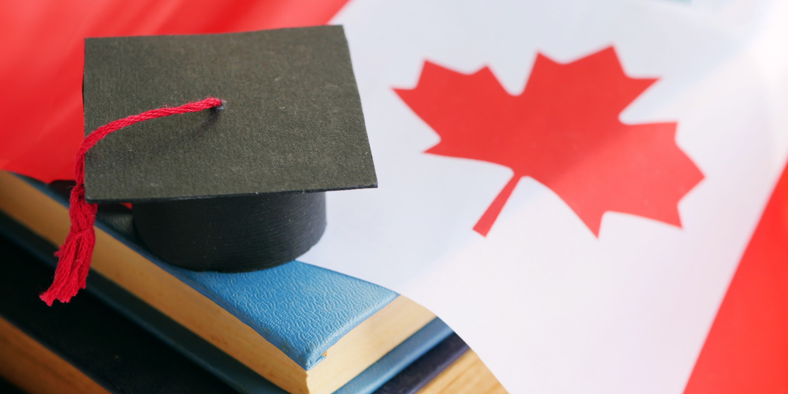 books and a graduation cap sitting on a Canadian flag