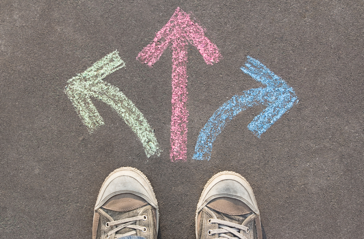 person wearing converse shoes standing in front of 3 chalk arrows point different directions