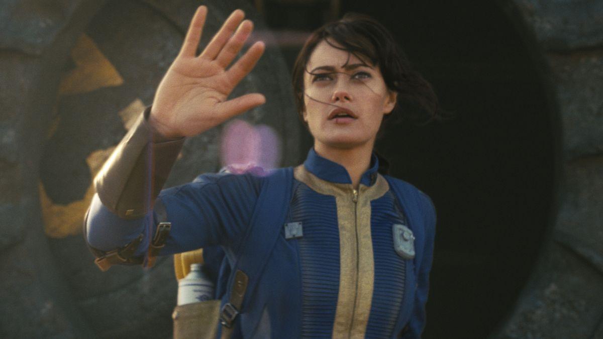 Ella Purnell as Lucy from fall out squinting and raising her arm