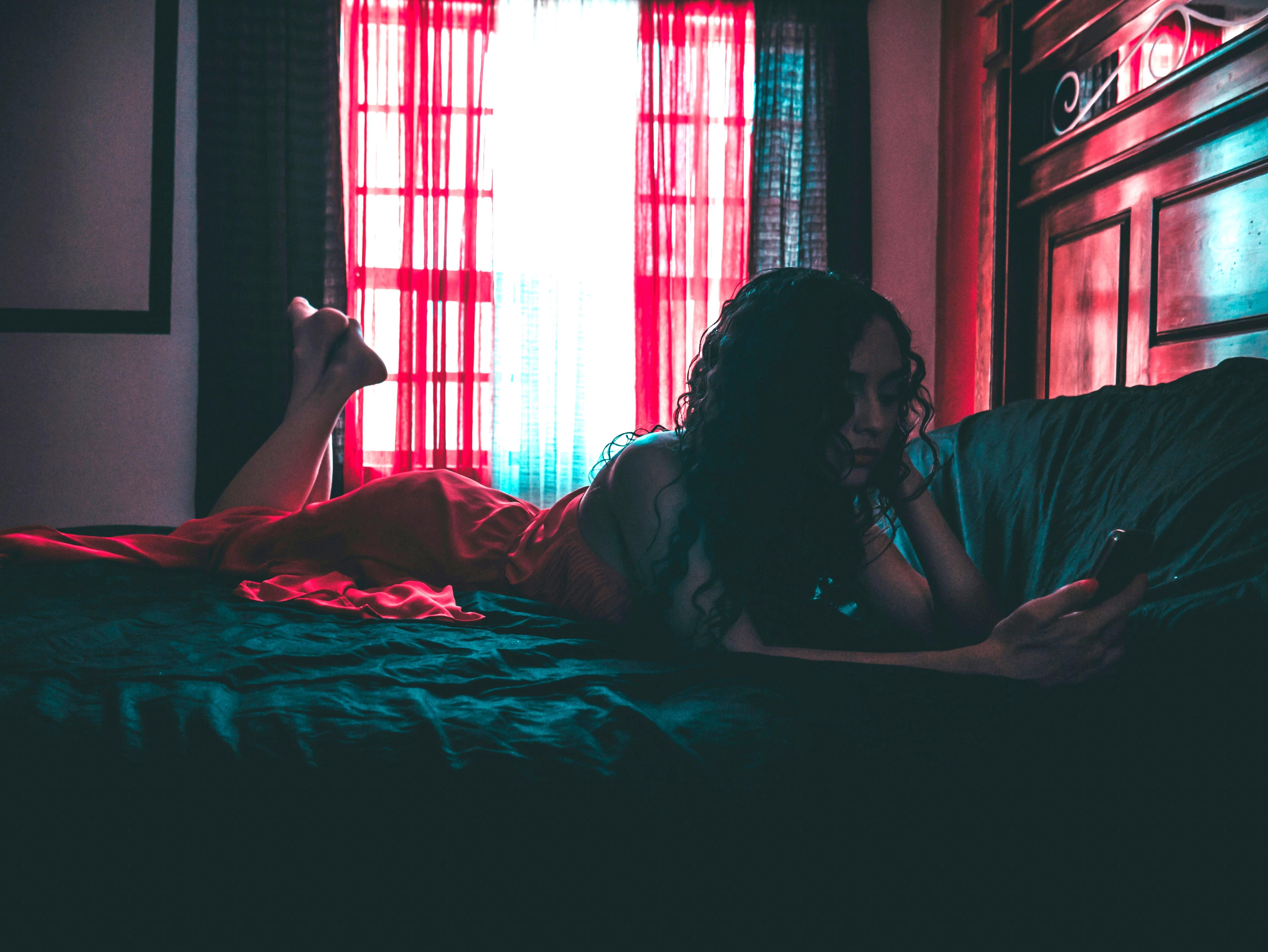 woman lying on a bed looking at her phone