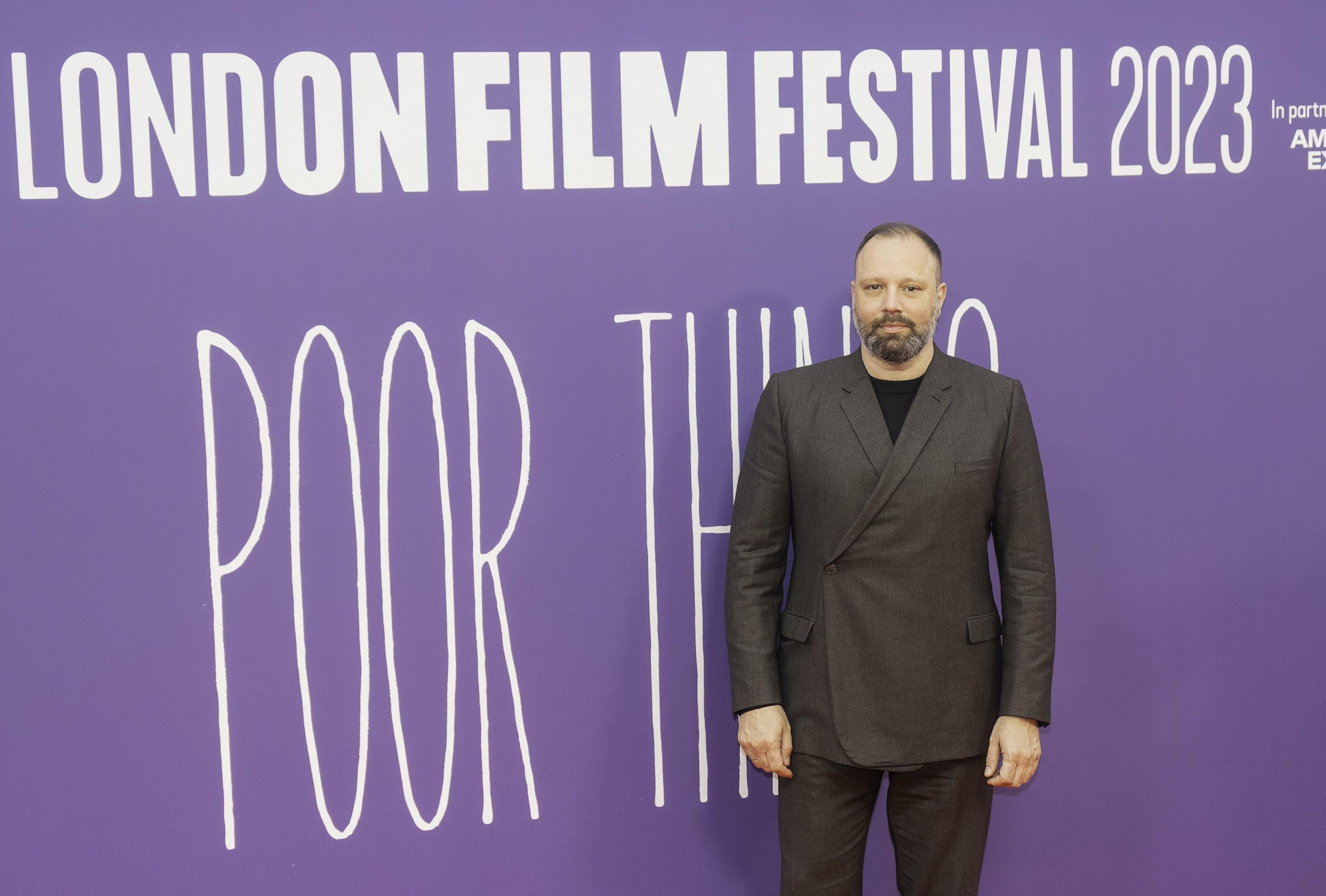 yorgos lanthimos standing in front of a purple backdrop