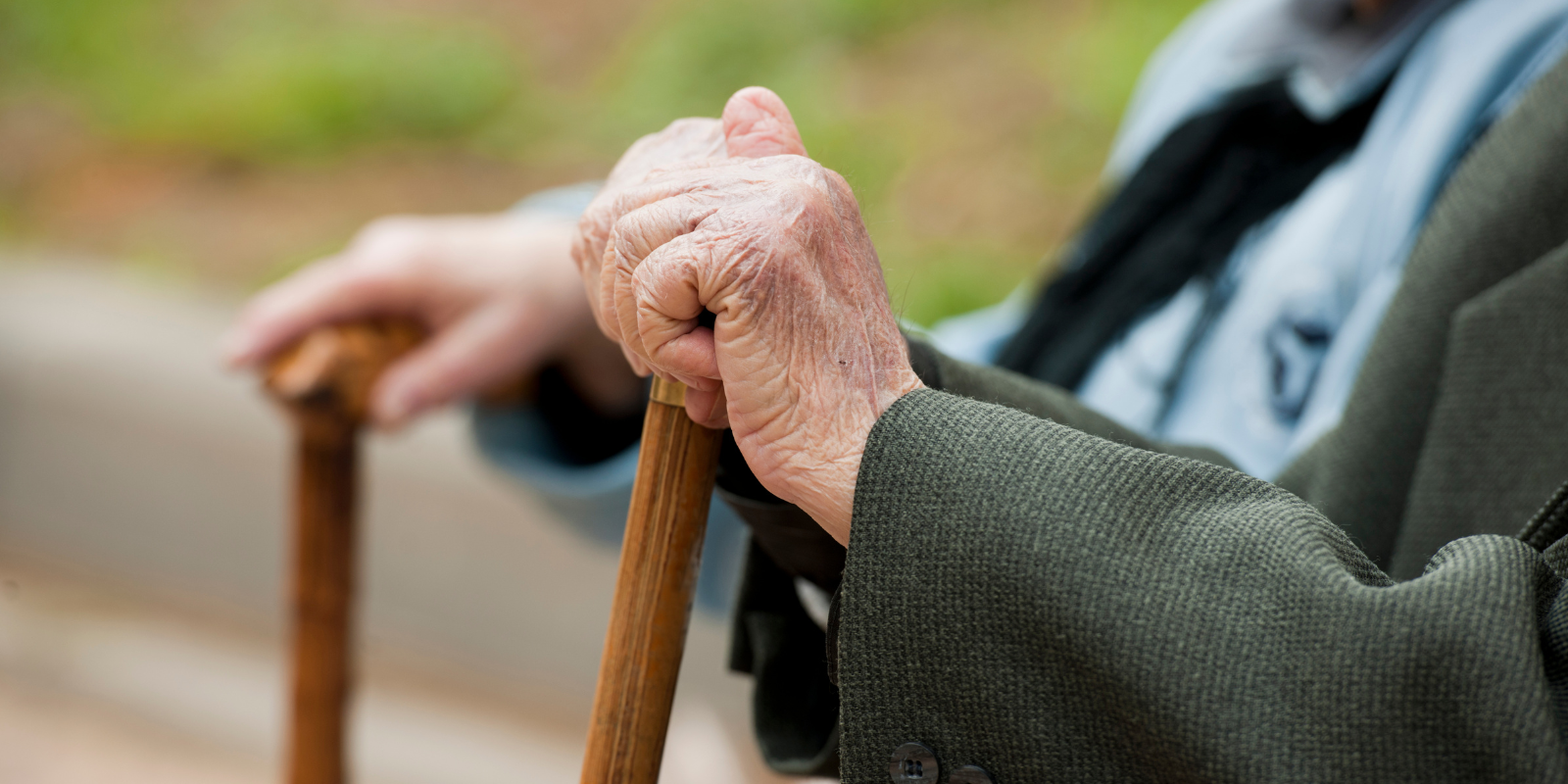 hands of elderly people resting on canes