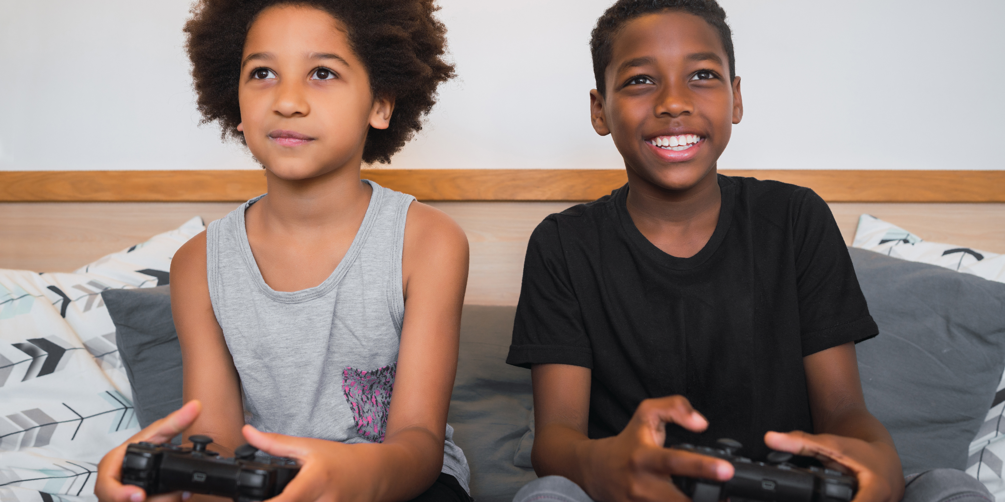 two young boys smiling and holding video game controllers 
