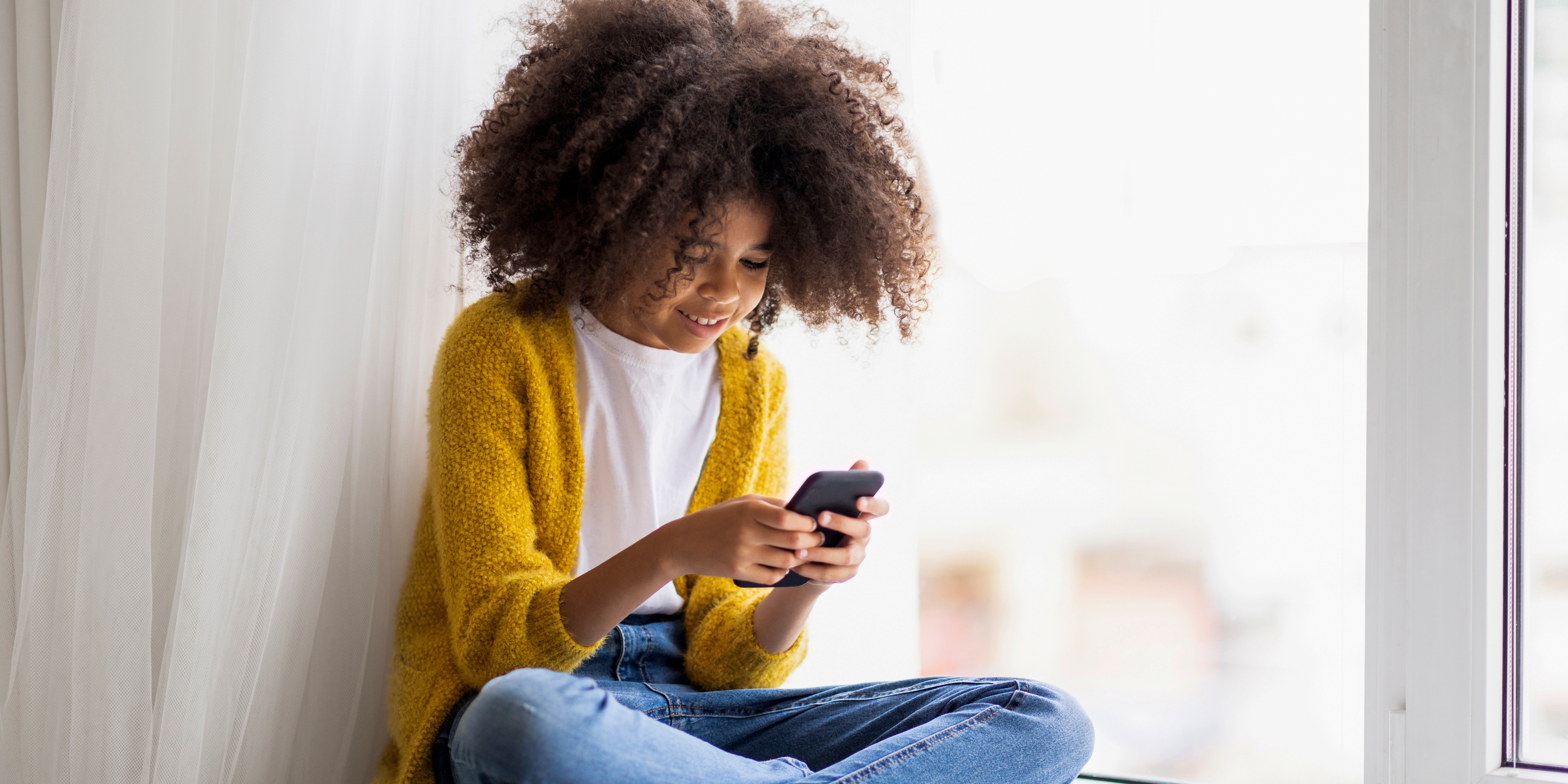 young black girl looking at her phone and smiling 