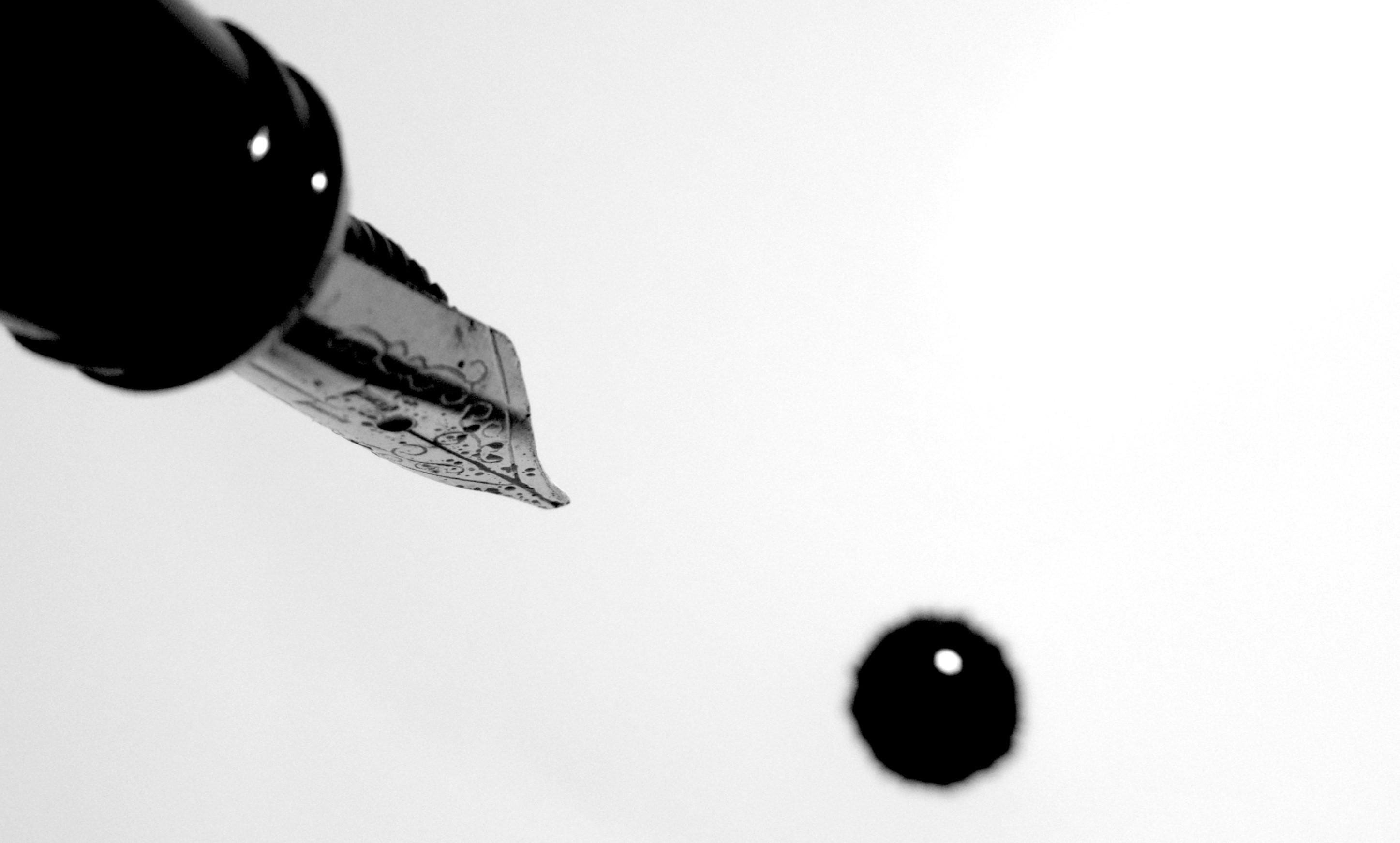 an ink quill on a white background with a drop of ink fallen from it
