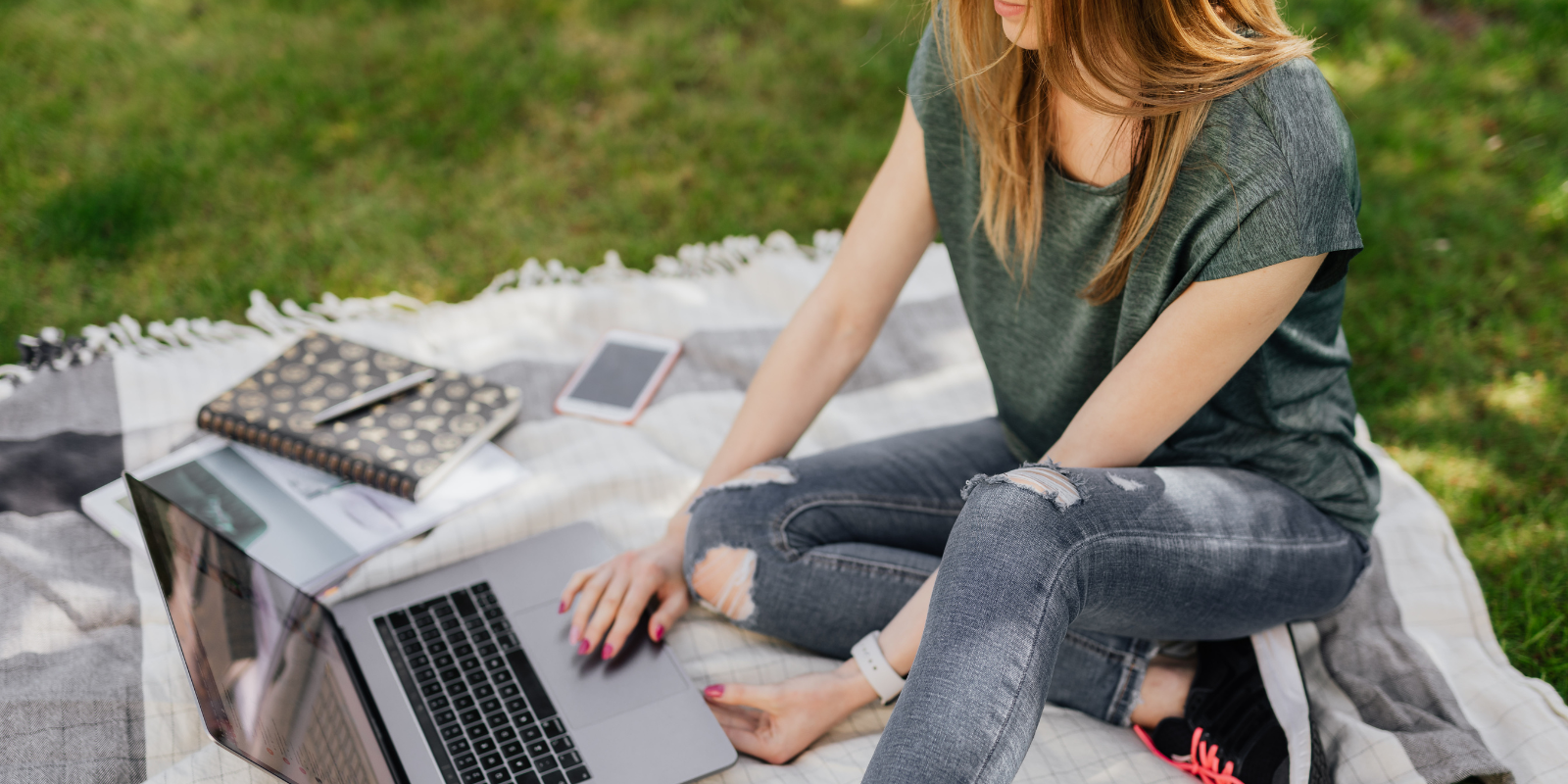a student sitting on a blanket on the grass studying