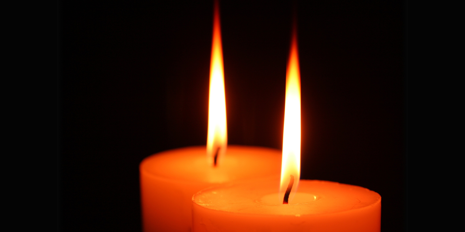two candles burning against a dark background