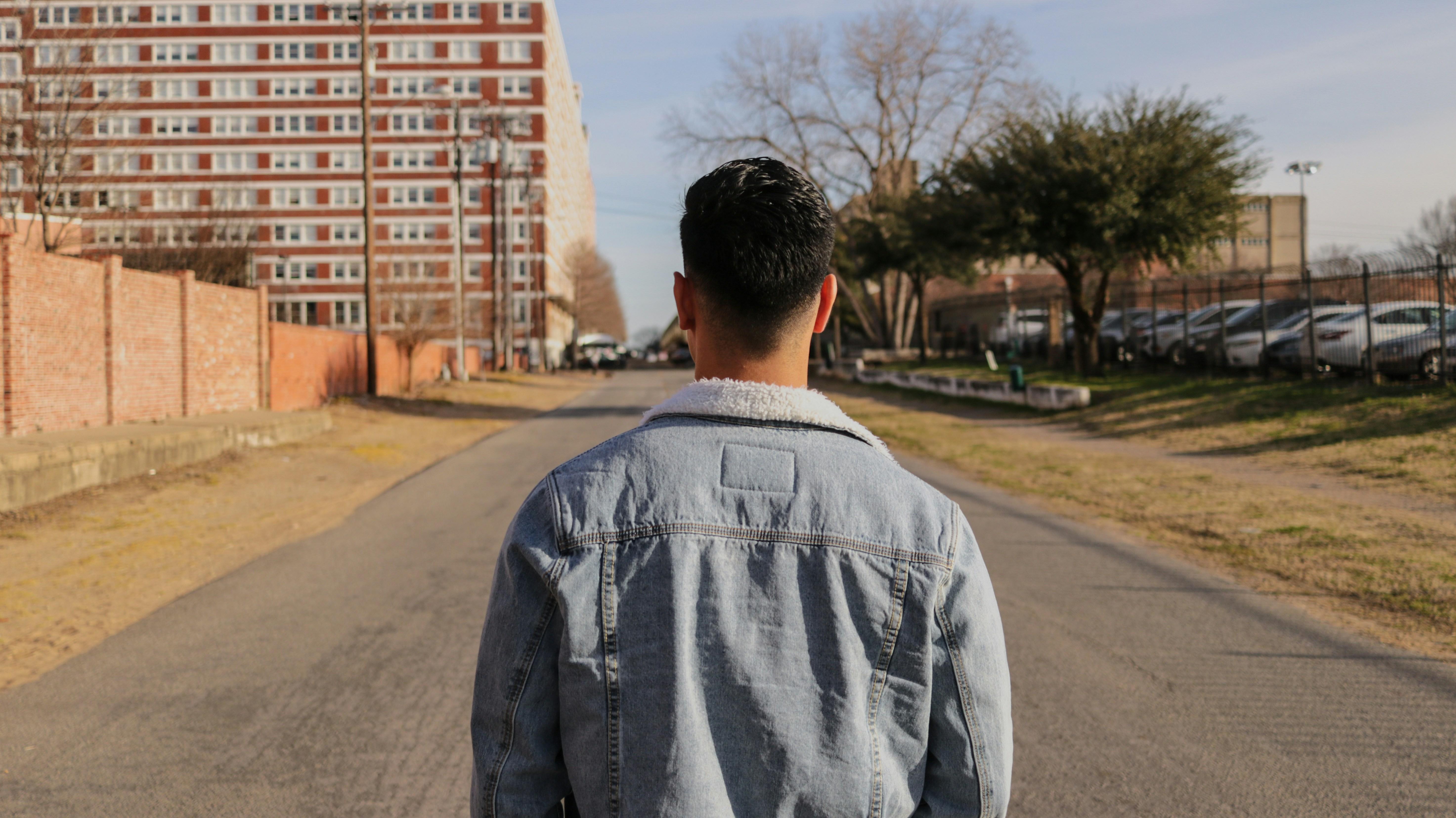 young man walking away from the camera on a quiet street