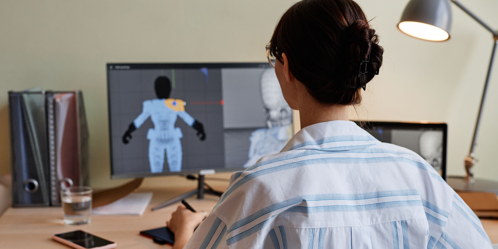 woman sitting in front of a computer working on an animated human figure 
