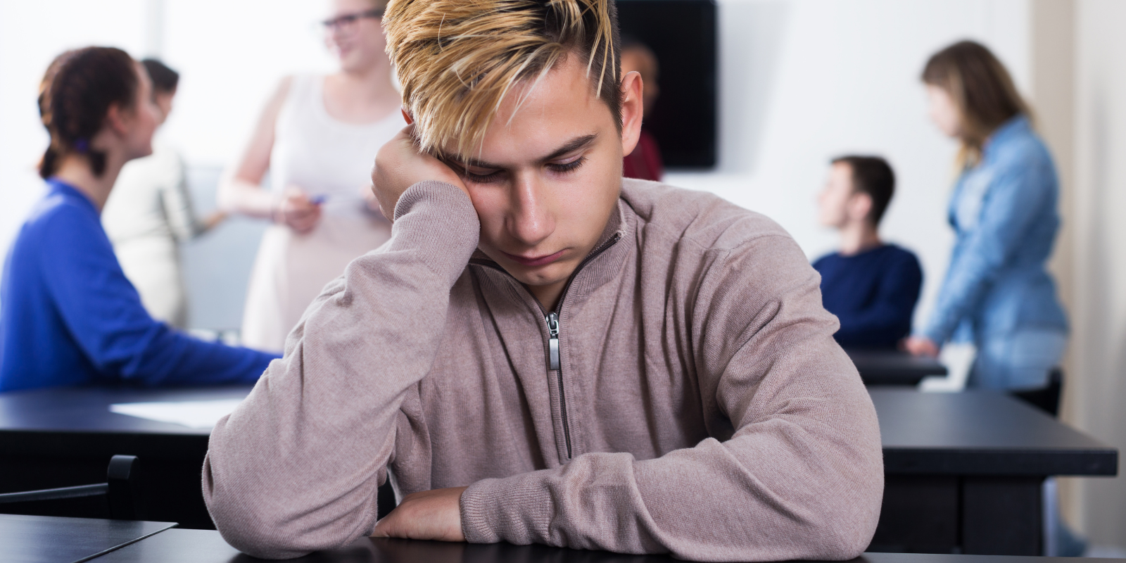 a student sitting at a desk looking sad 
