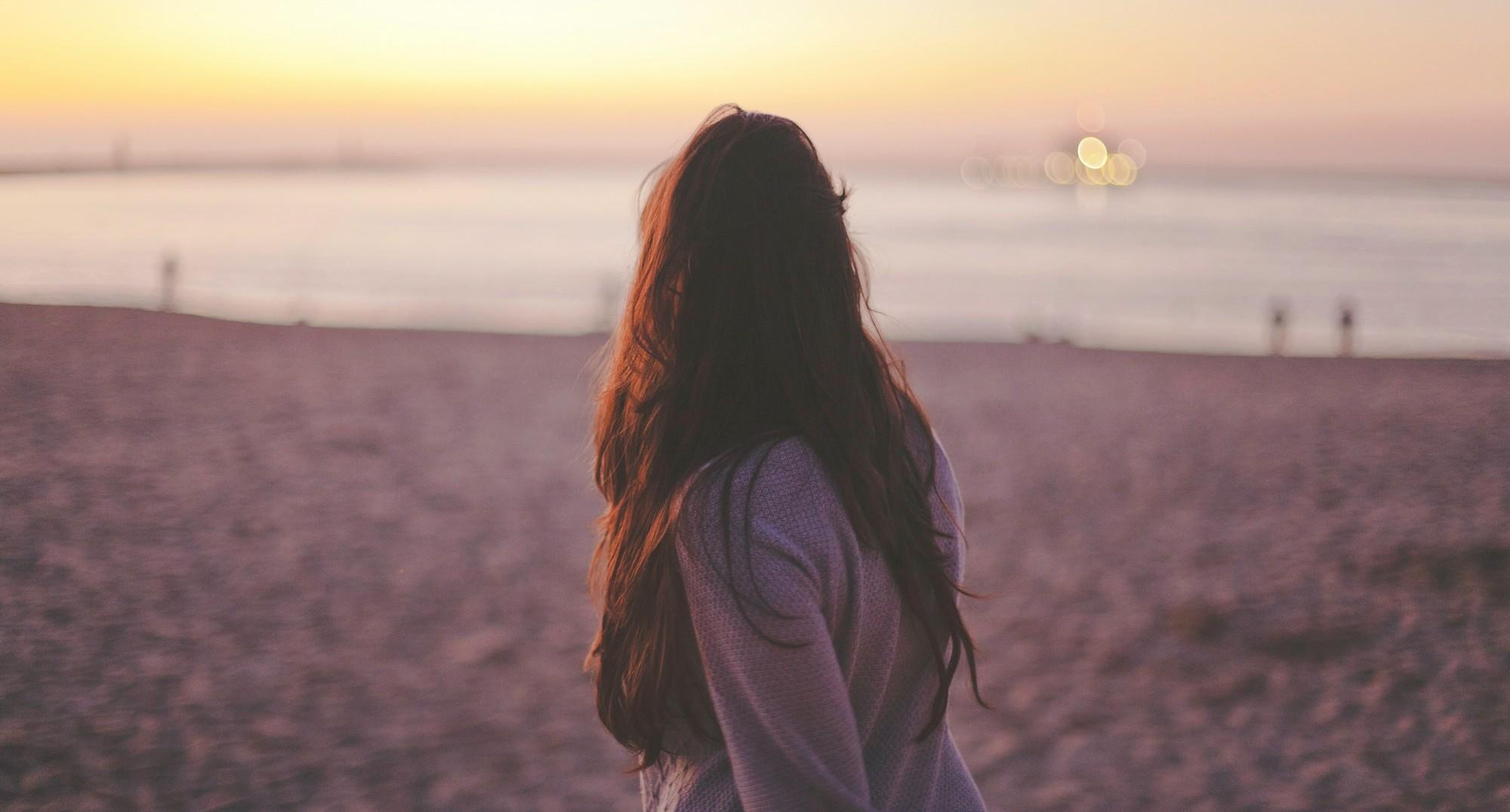 woman walking on the beach with her back towards the camera