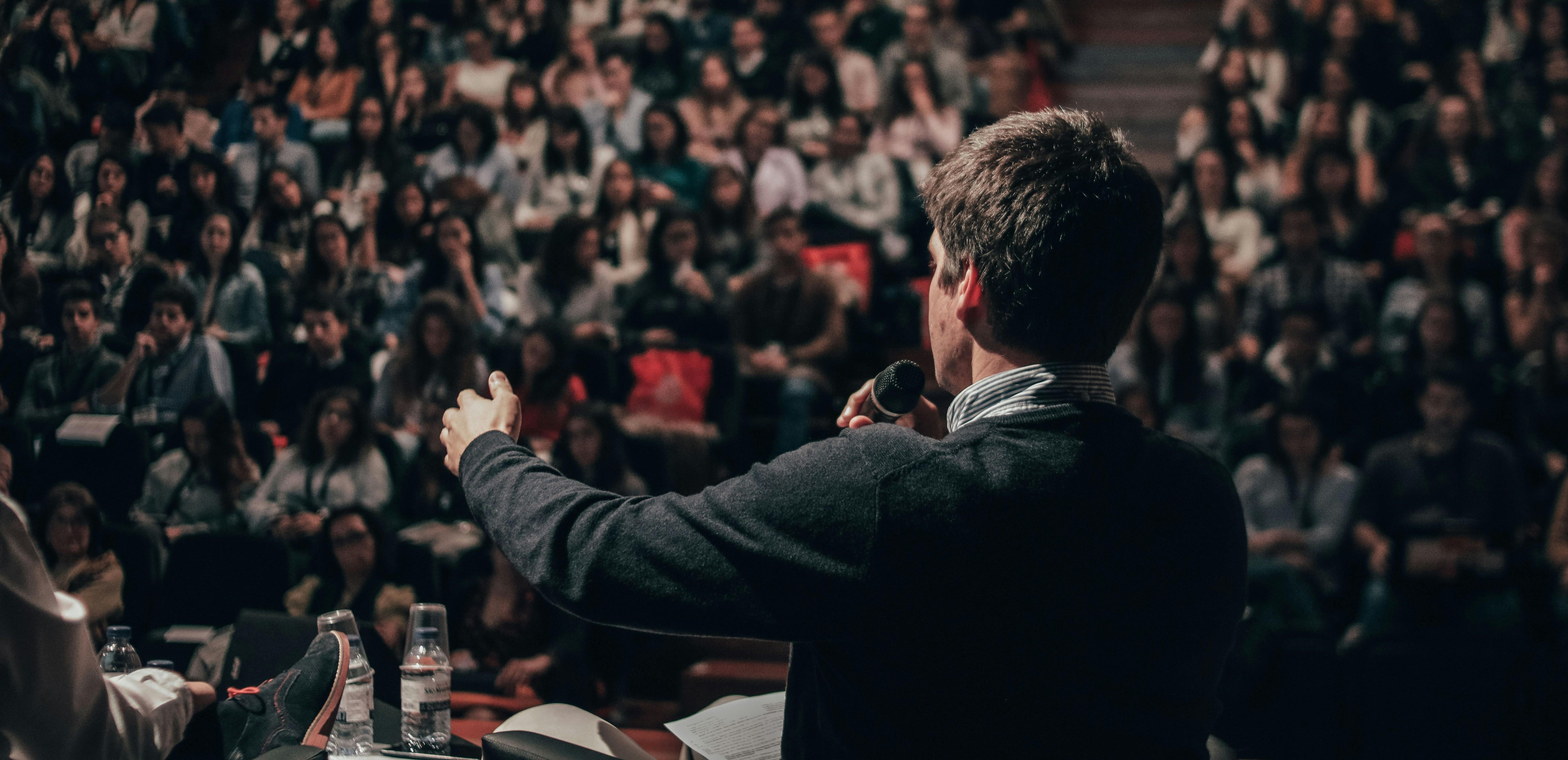 a young man talking to a crowd through a microphone