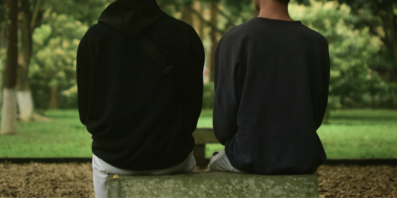 two people sitting on a park bench