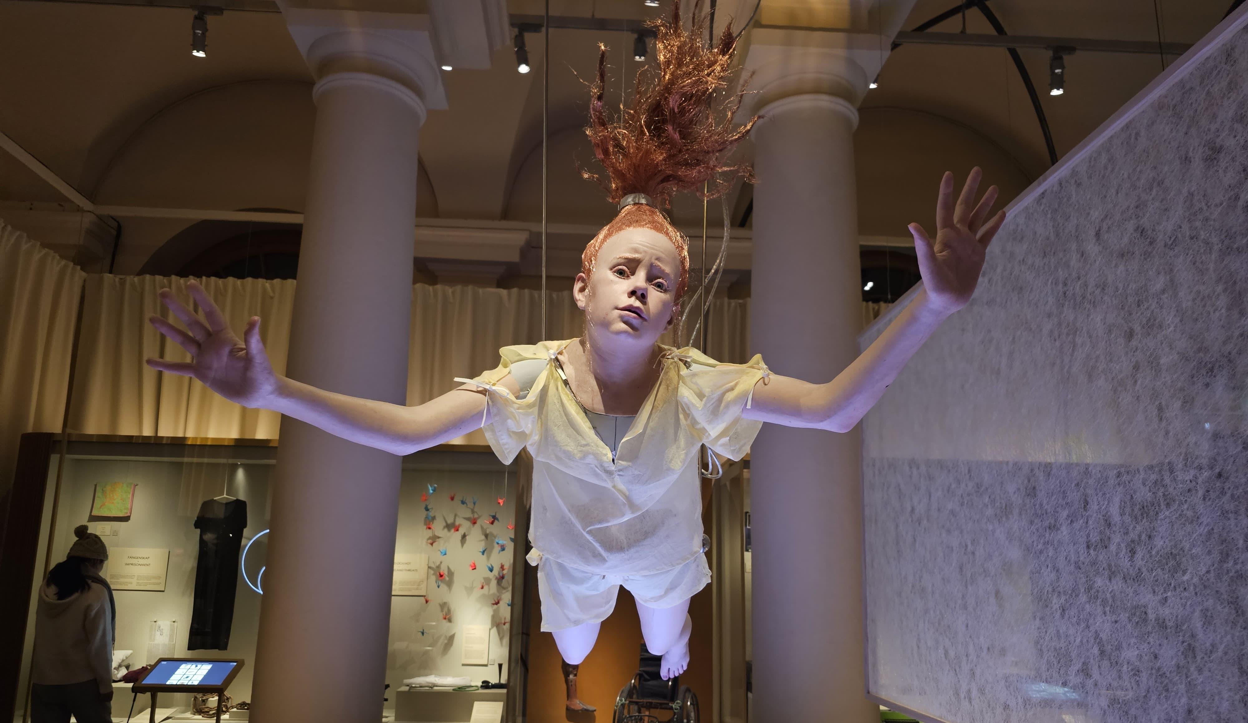 A model of a young girl suspended from the ceiling