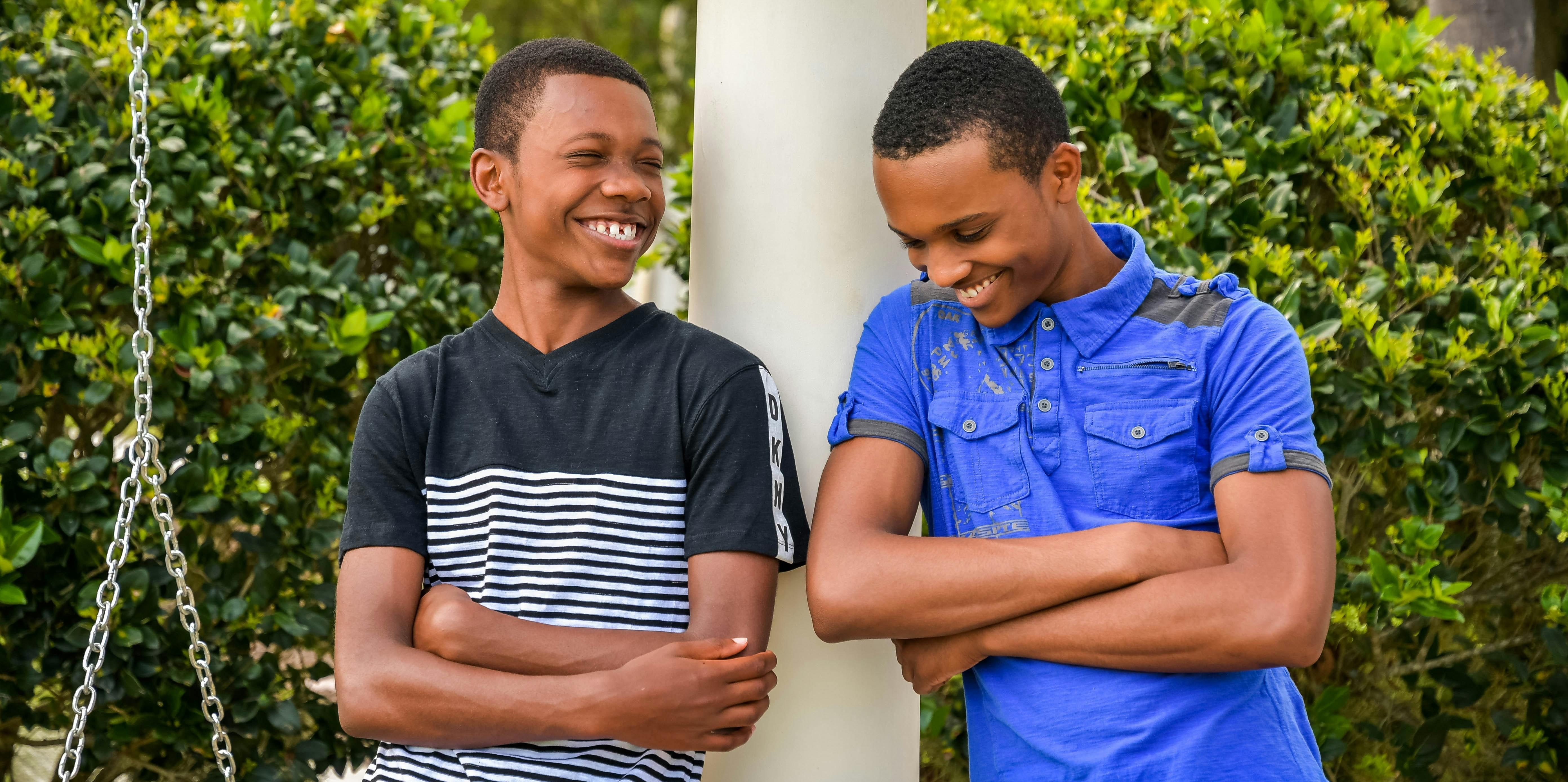 two boys standing outside laughing with each other 