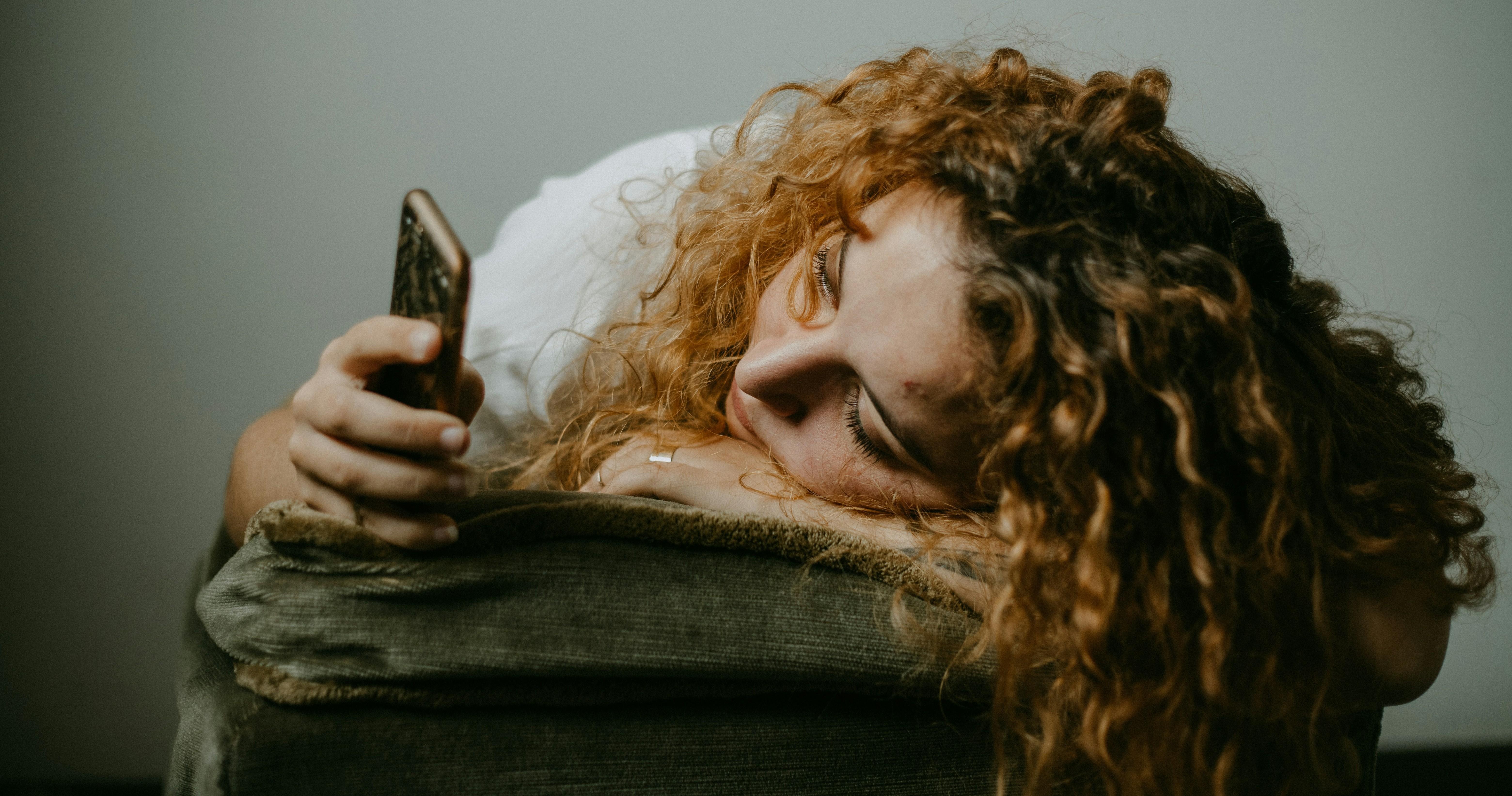 young woman laying on her arm and scrolling through her phone