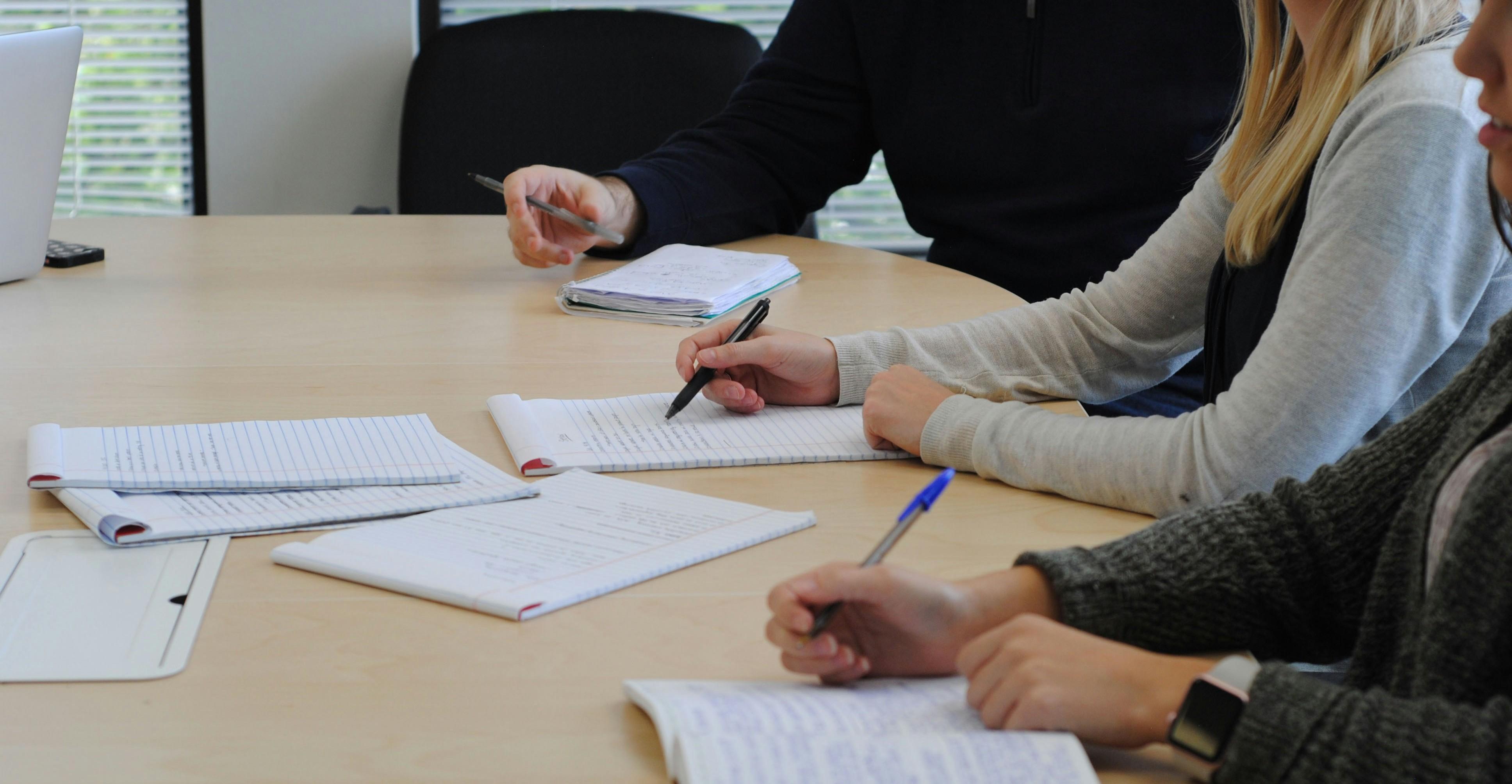 a few people sitting at a table taking notes