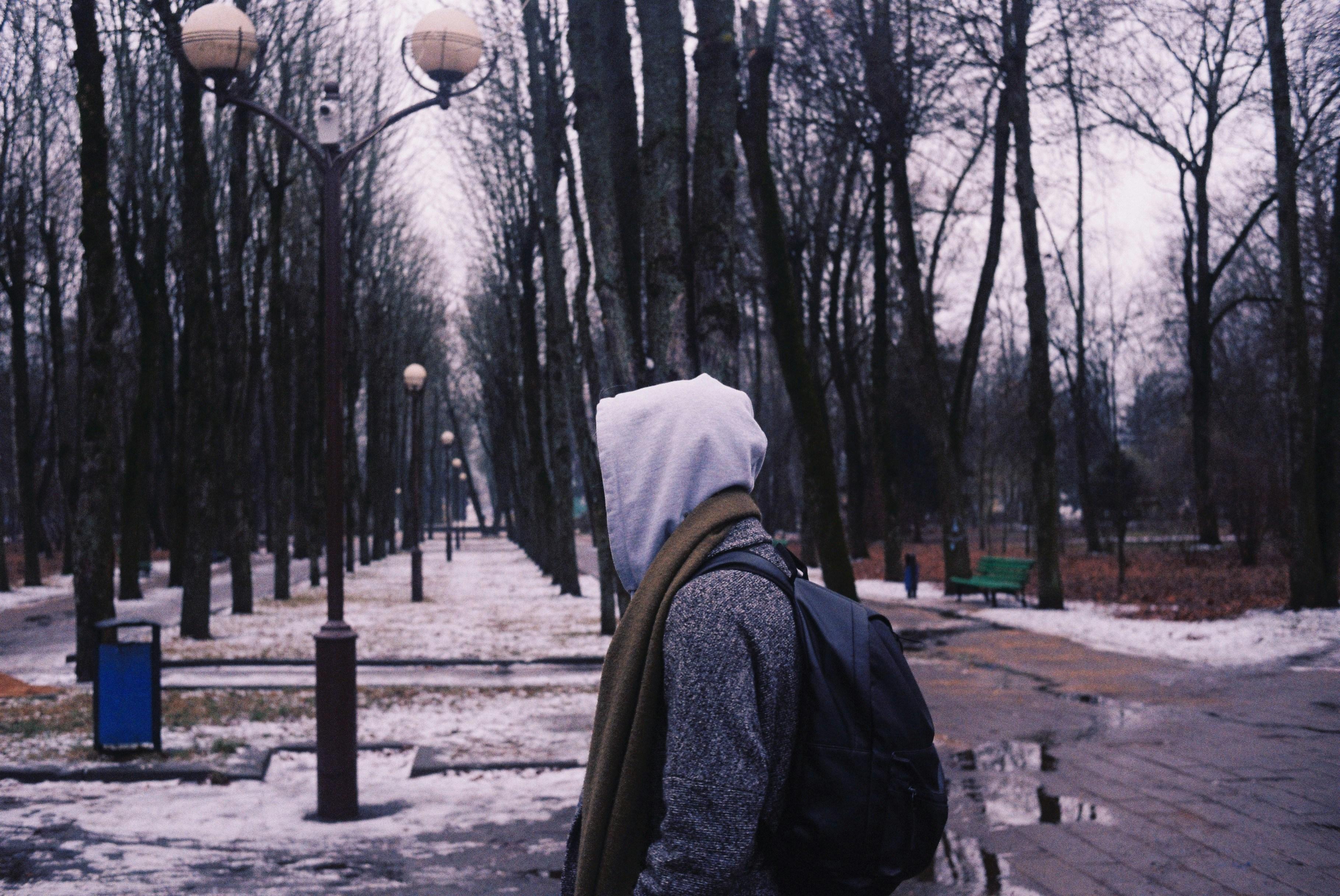 young man walking through a park with his hood up