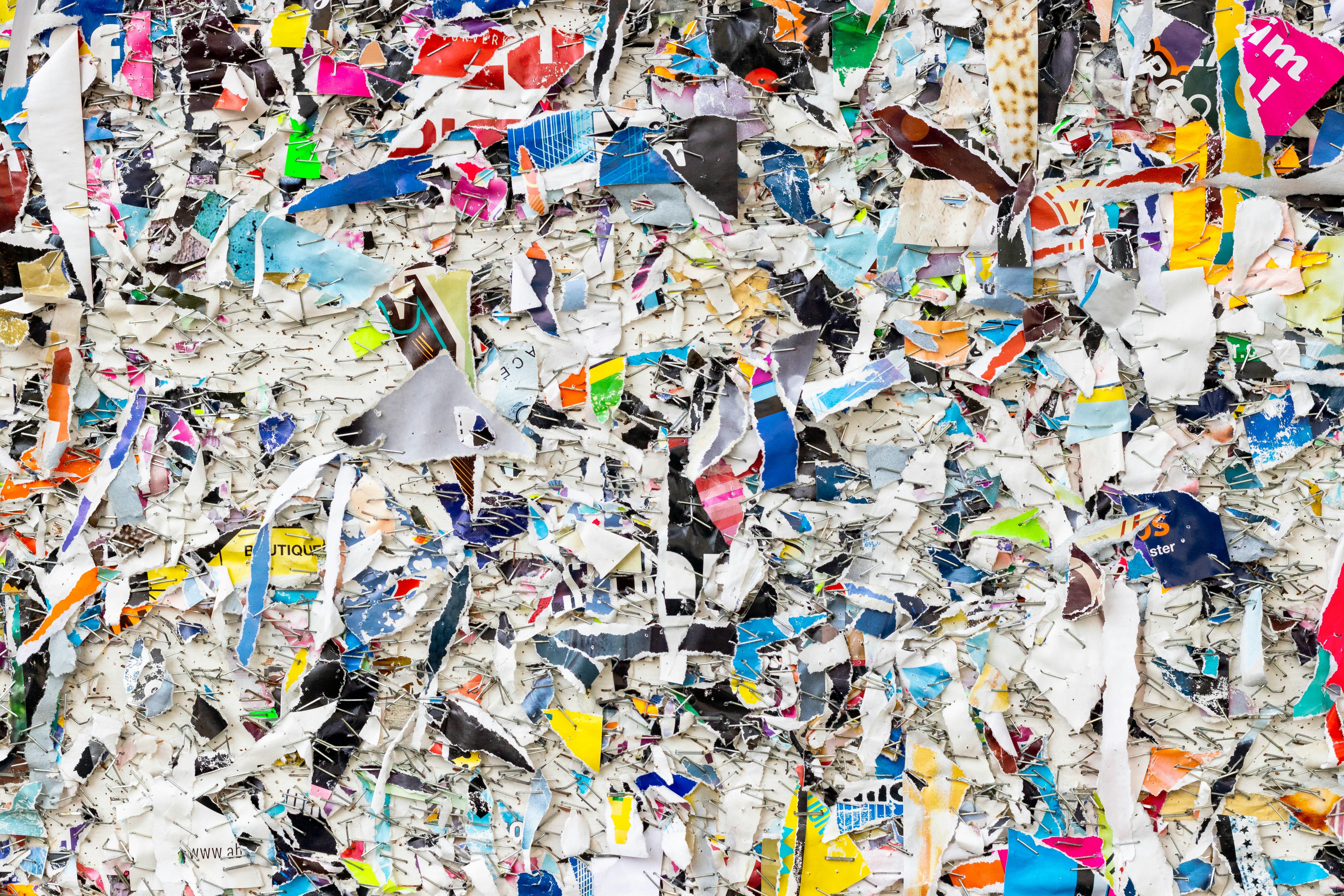 Colorful collage of remains of posters on street posters wall. Pieces of paper with steel staples.