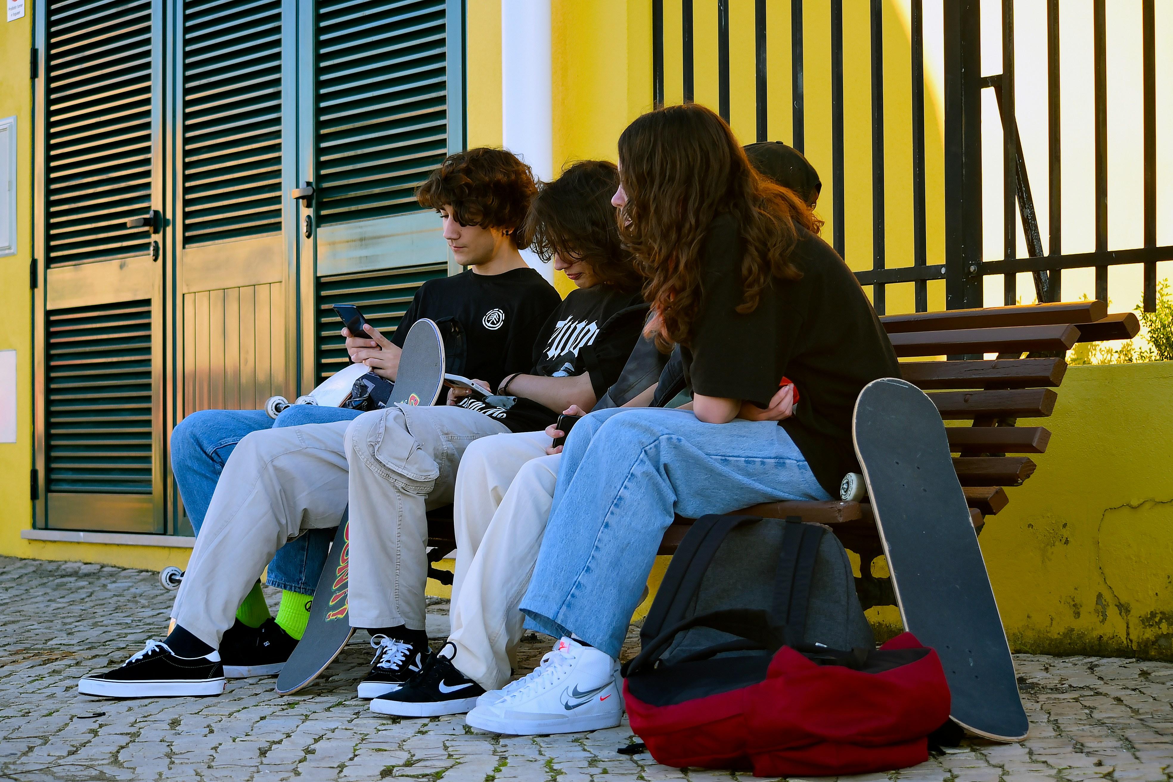 Four young people on a bench with skateboards