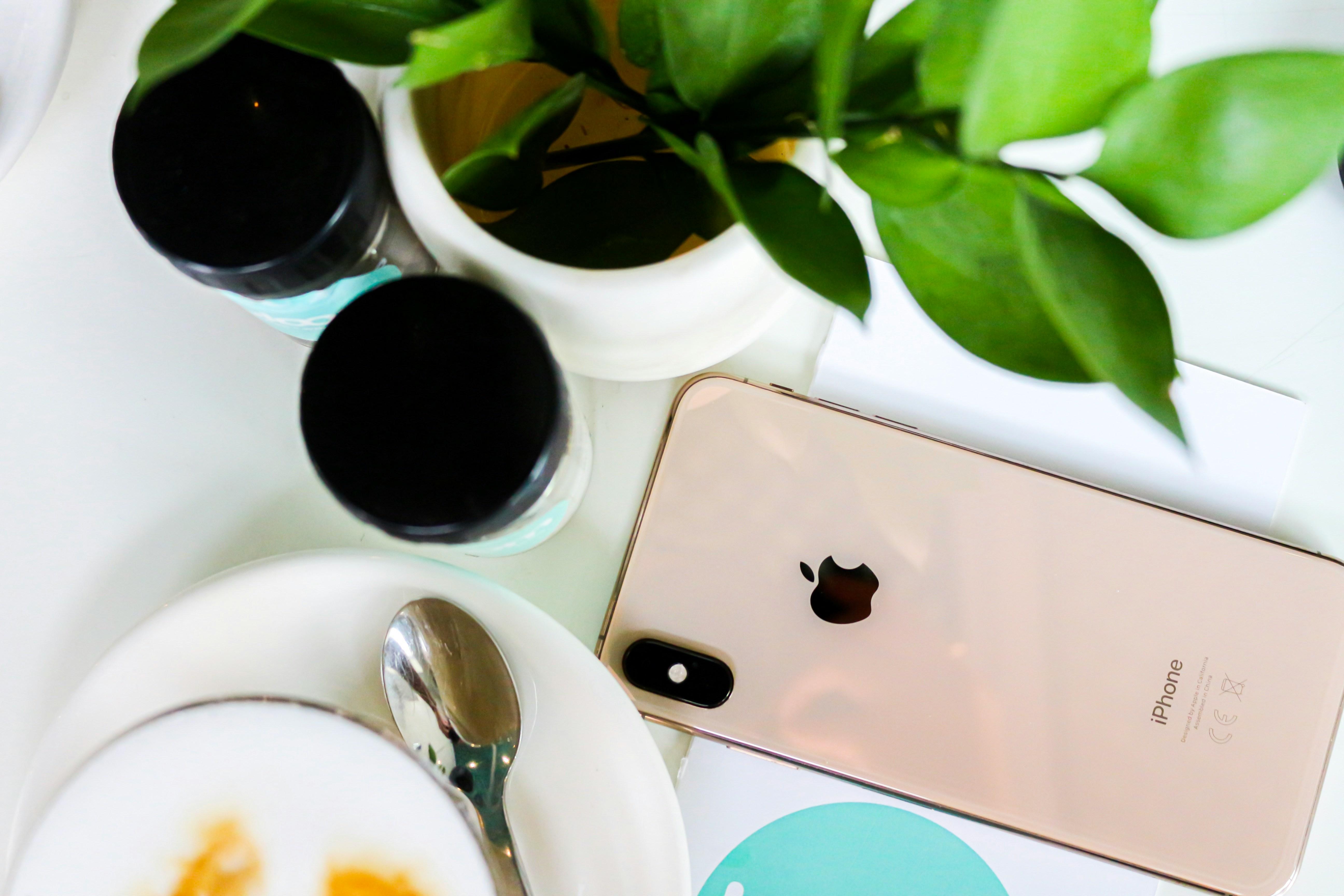 An over view of an Iphone on a table next to some supplement bottles and a coffee. 