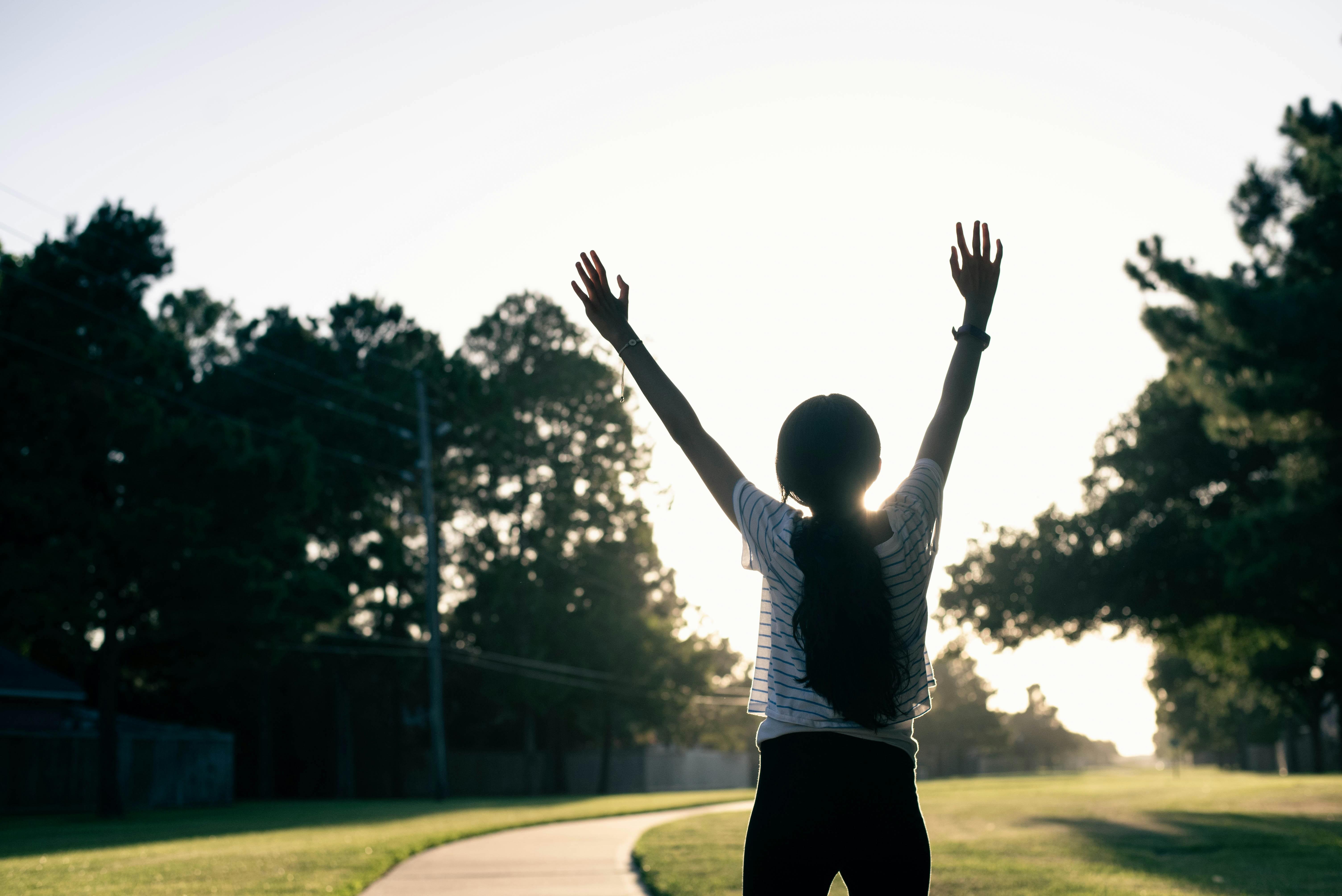 A silhouette of a young girl with her arms in the air.