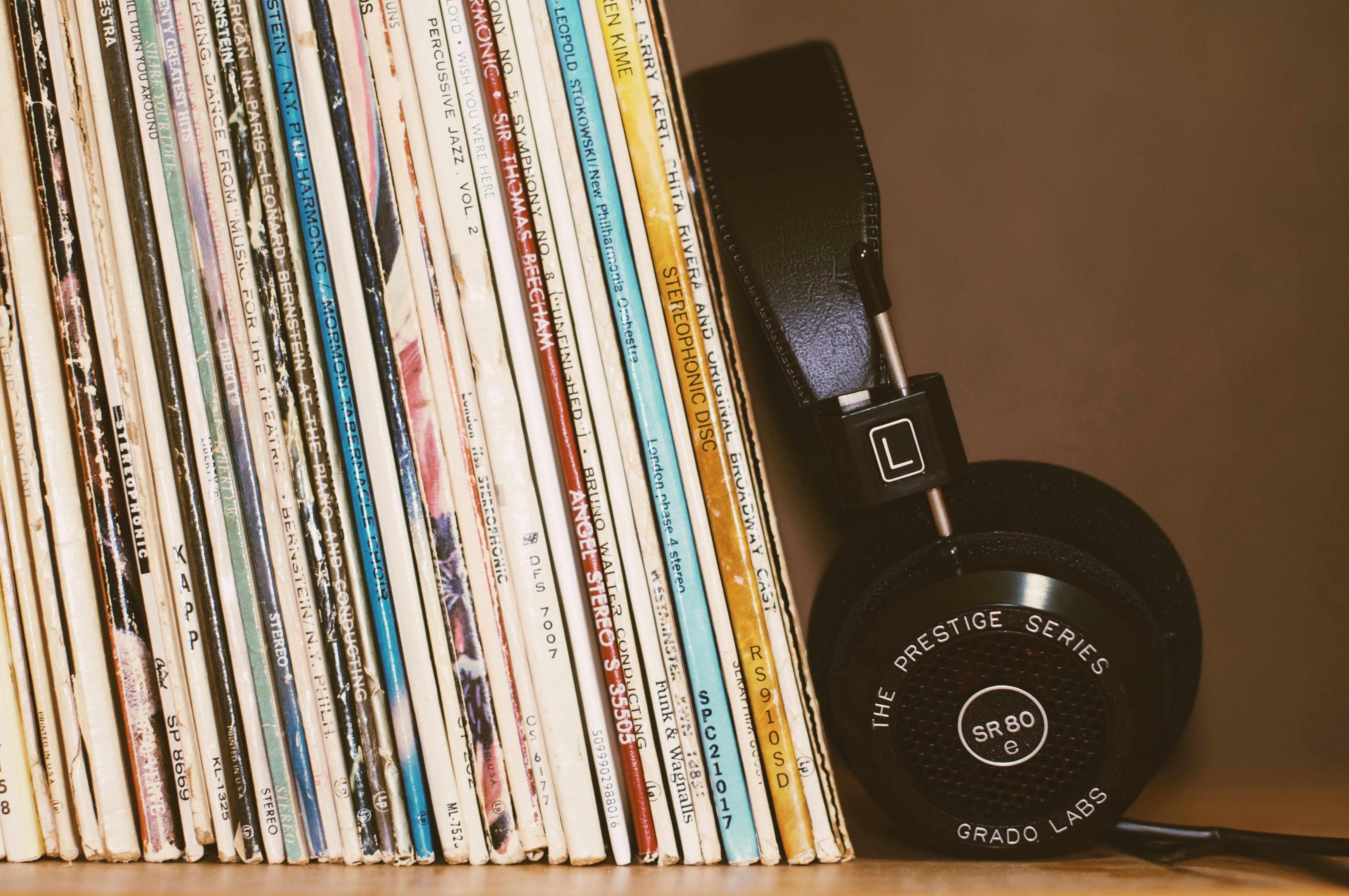A stack of records next to a set of headphones.