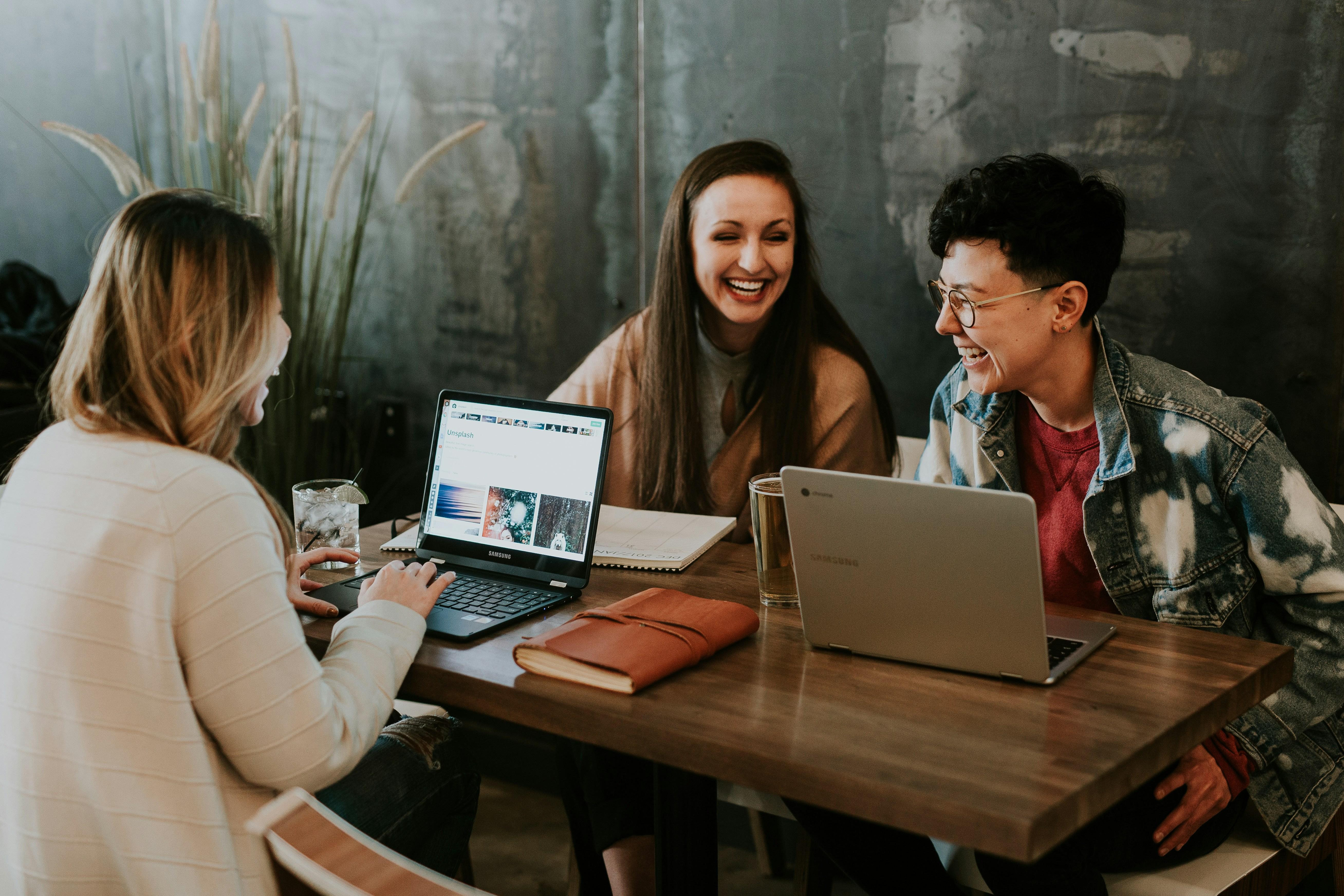 Three young people networking at a table together.