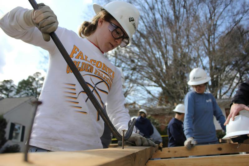 A young woman using a crowbar for woodworking.