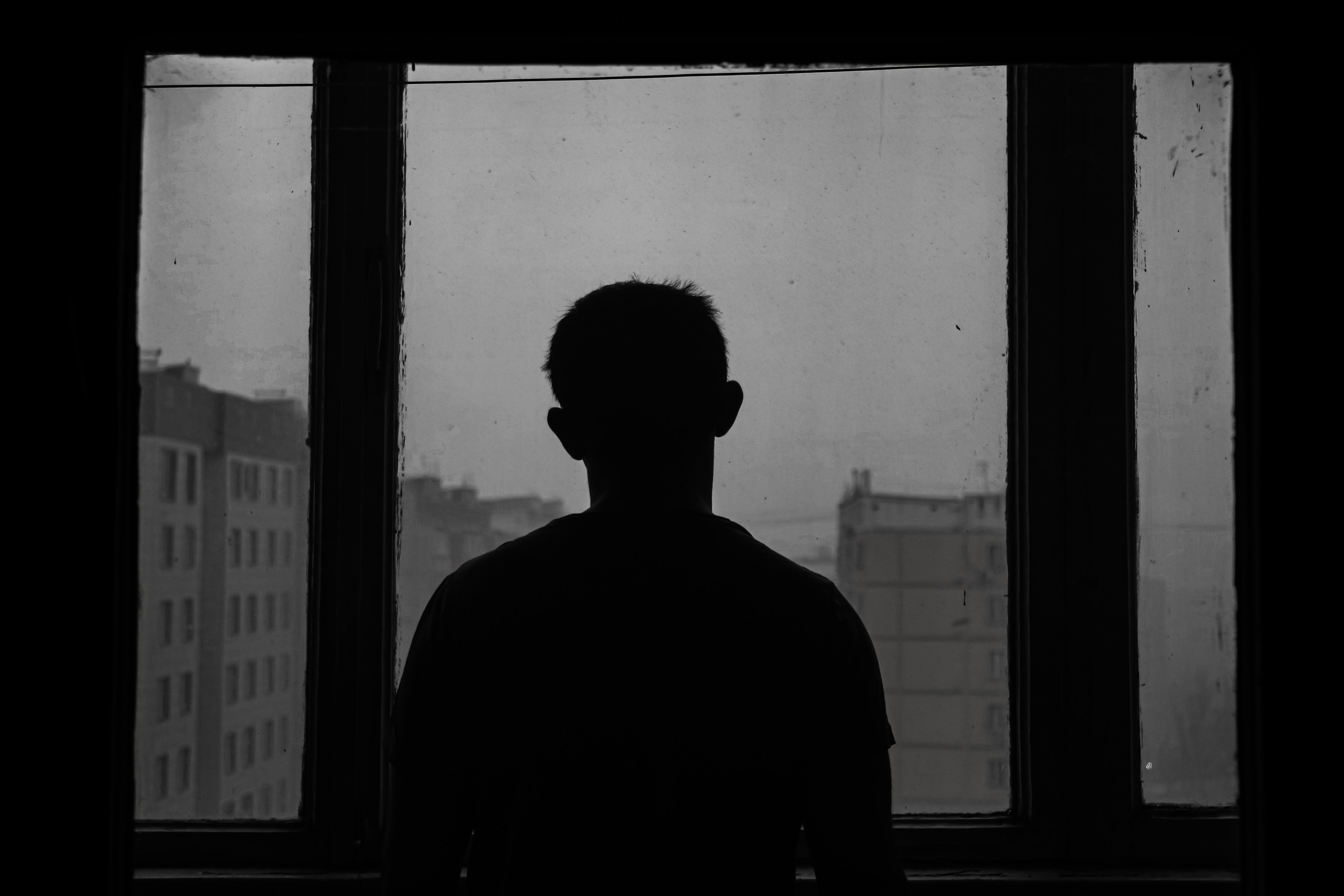 silhouette of man standing near a window