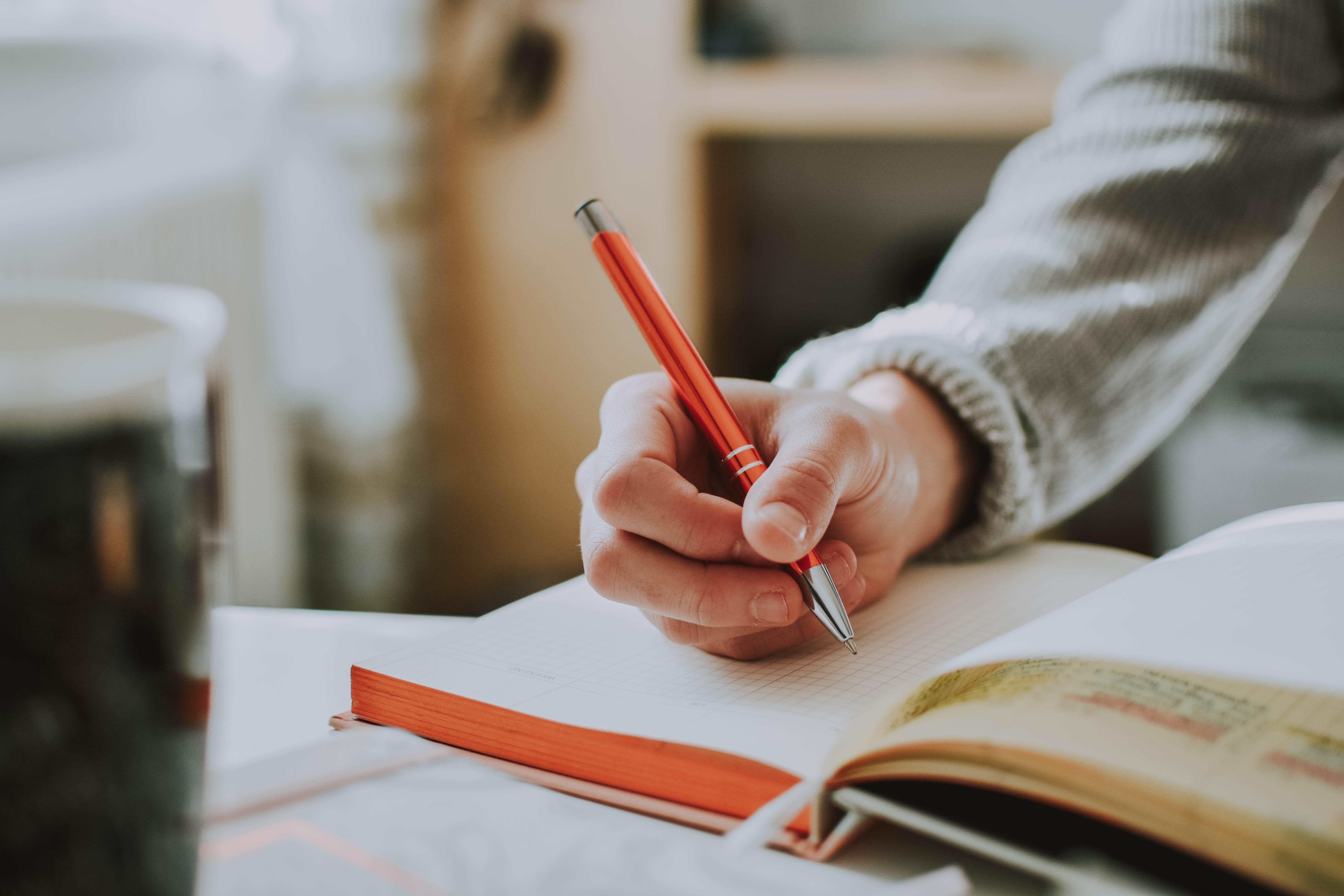 person writing in a journal at a desk