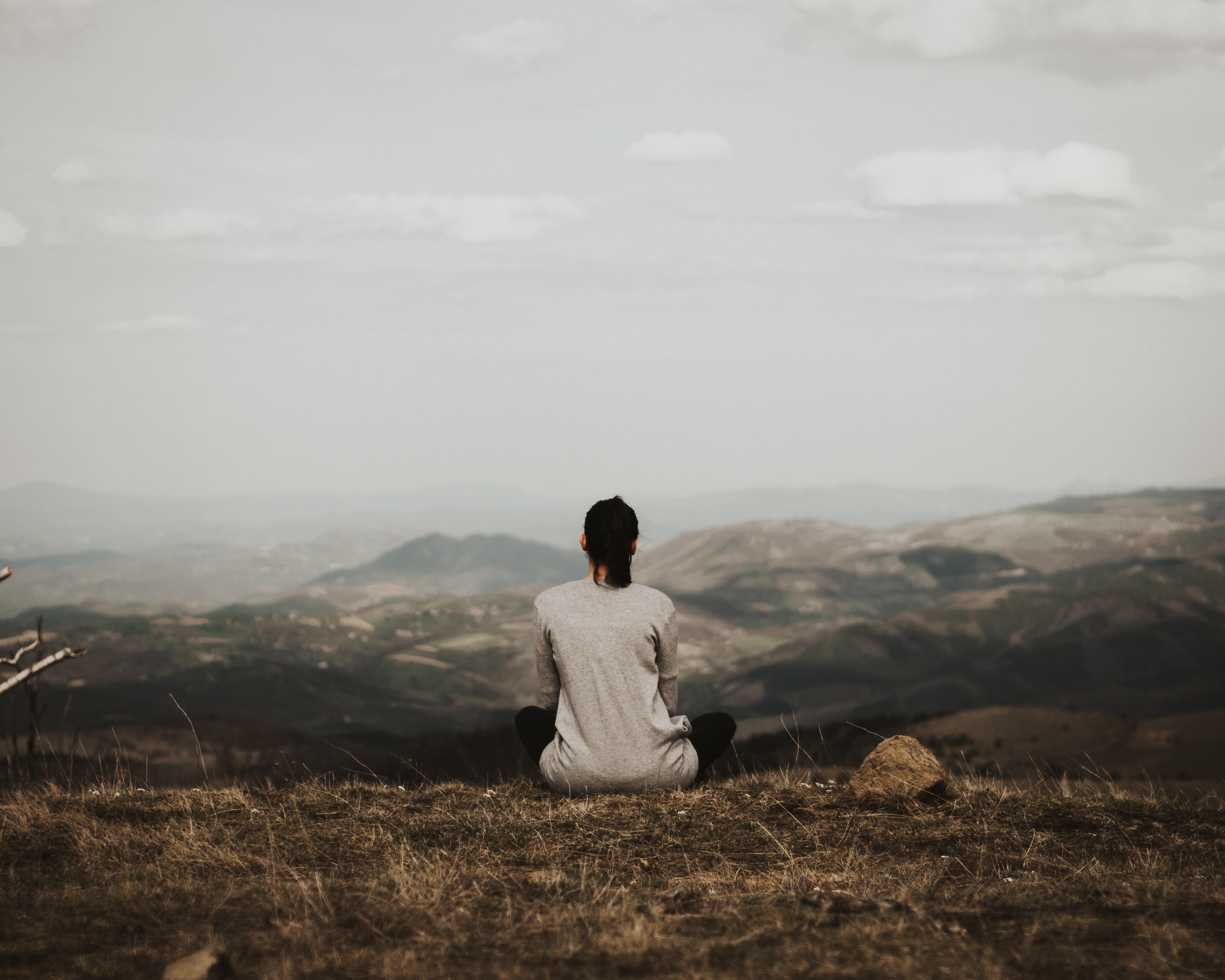 Woman sitting on a cliff looking out onto the view