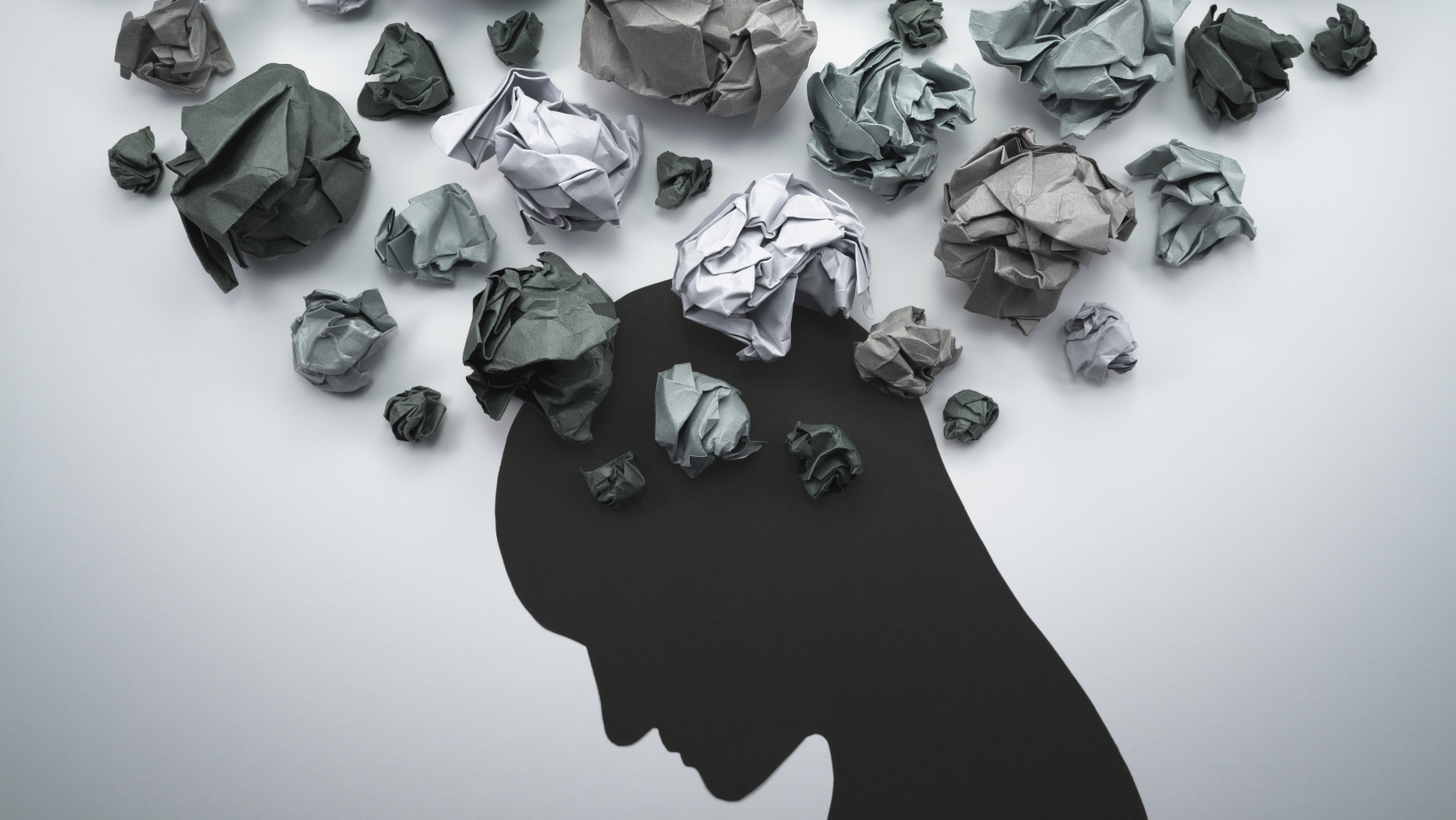 a silhouette of a human head with gray balls of paper surrounding it