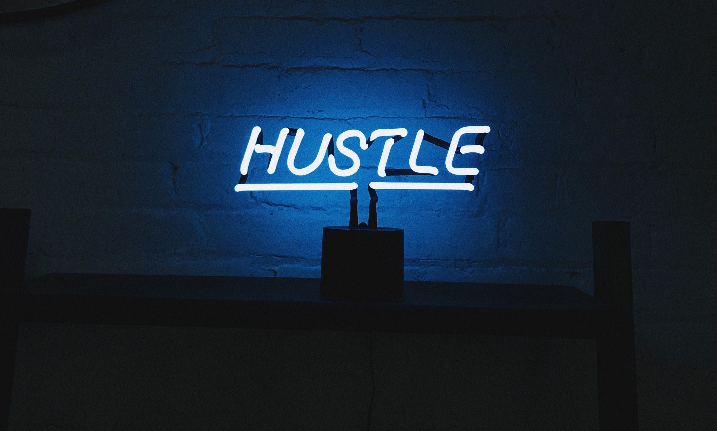 neon light that says "hustle"