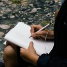 person sitting and sketching in a notebook