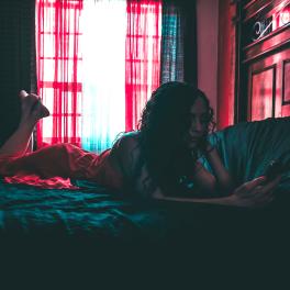 woman lying on a bed looking at her phone