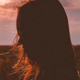 silhouette of a young woman's face against a sunset backdrop