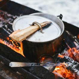 a pot with a lid sitting over a campfire