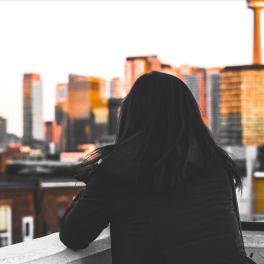 woman standing on a rooftop looking out on a city