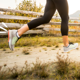 legs in black leggings and sneakers running on a path